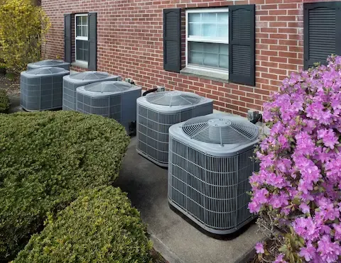 Row of commercial HVAC units outside brick building serviced by Woodburn HVAC