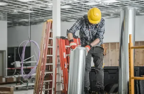 HVAC technician preparing metal ductwork on job site for Woodburn Heating & Cooling.