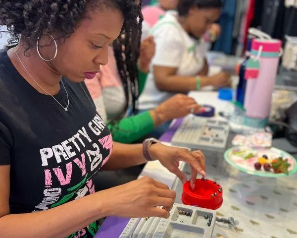 Women creating healing crystal bracelets at a Sip and String party in National Harbor. Guests are smiling and enjoying drinks while stringing beads together in a bright, welcoming setting.