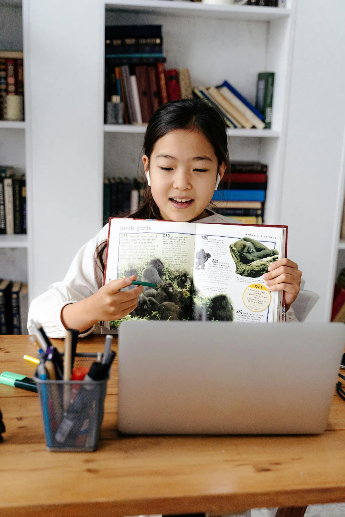 Student showing book contents to virtual classmates via laptop