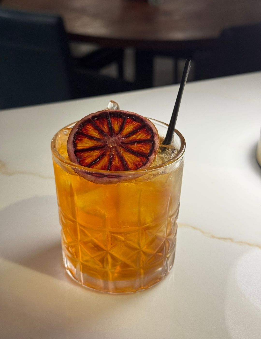 An iced amber drink in a tall glass on a wooden table