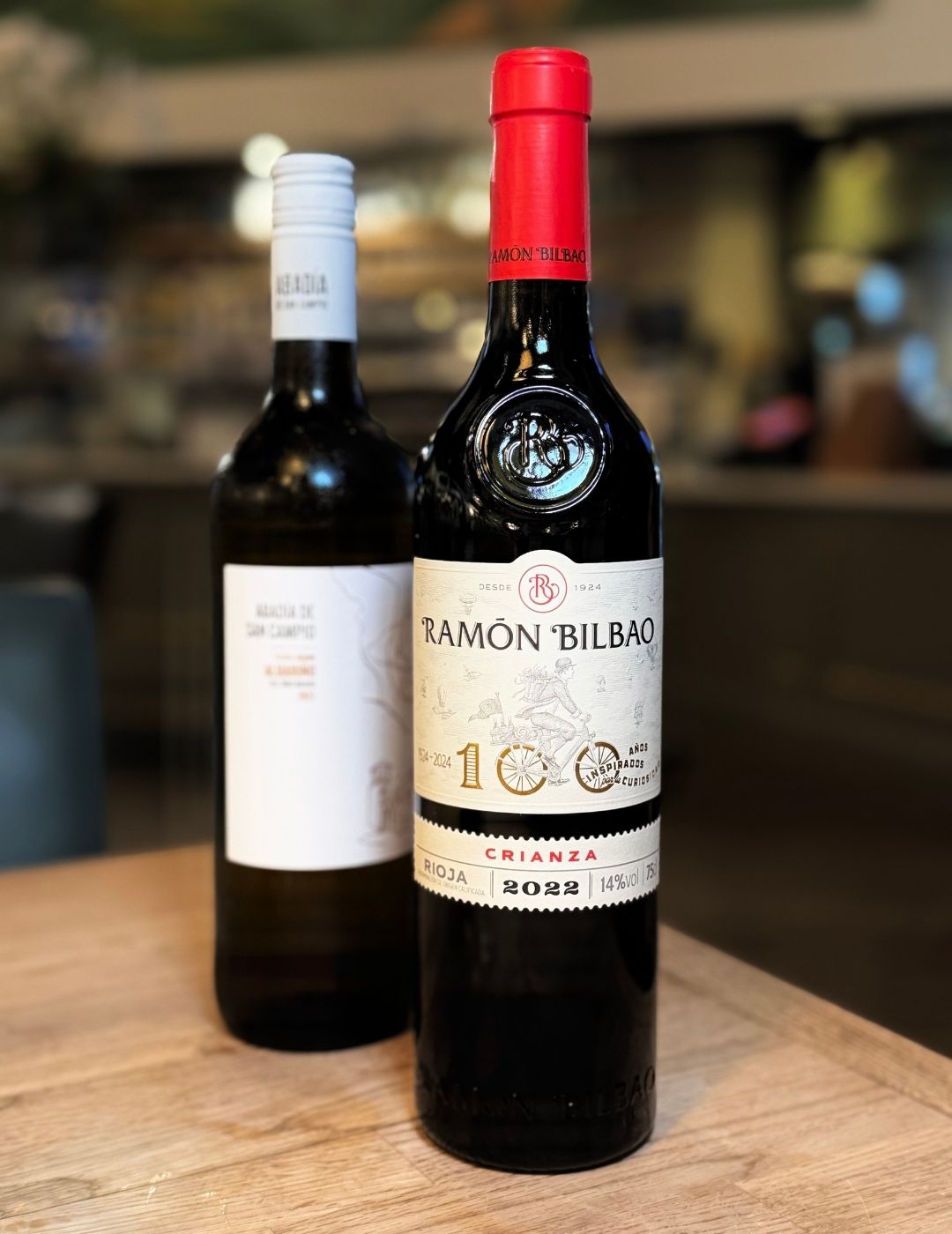 Two bottles of red wine displayed on a wooden surface