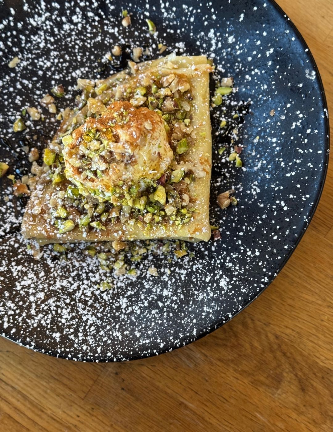 Dark spiced flatbread or pastry slice on a dark plate on a wooden table