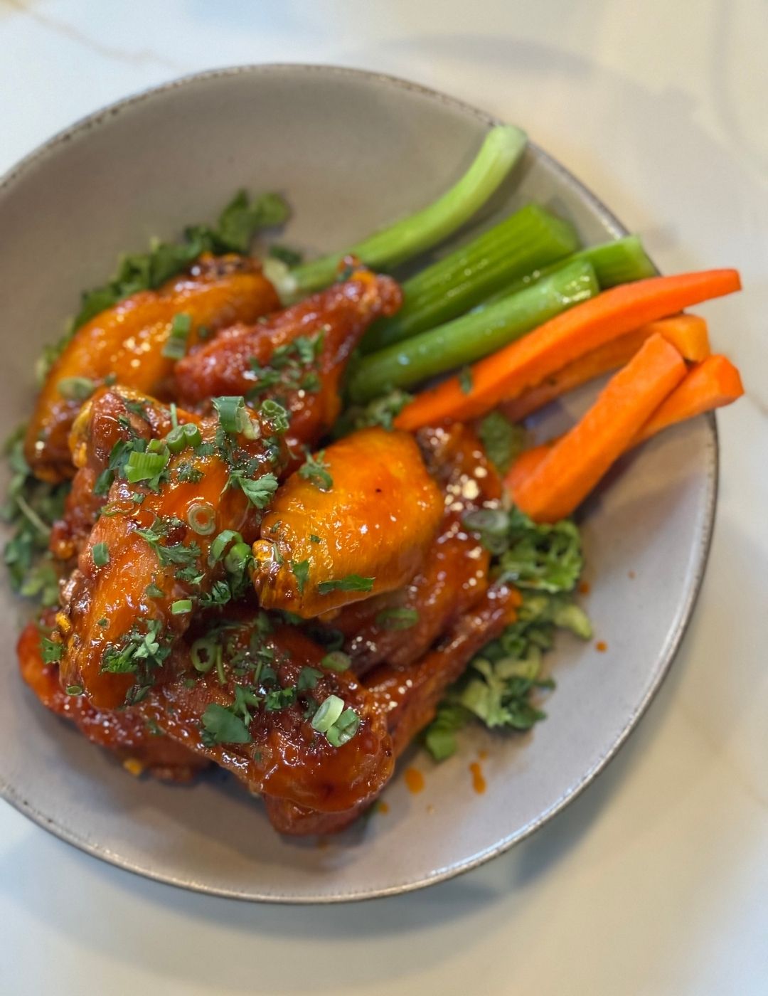 A bowl of colorful roasted chicken and vegetables including carrots and greens