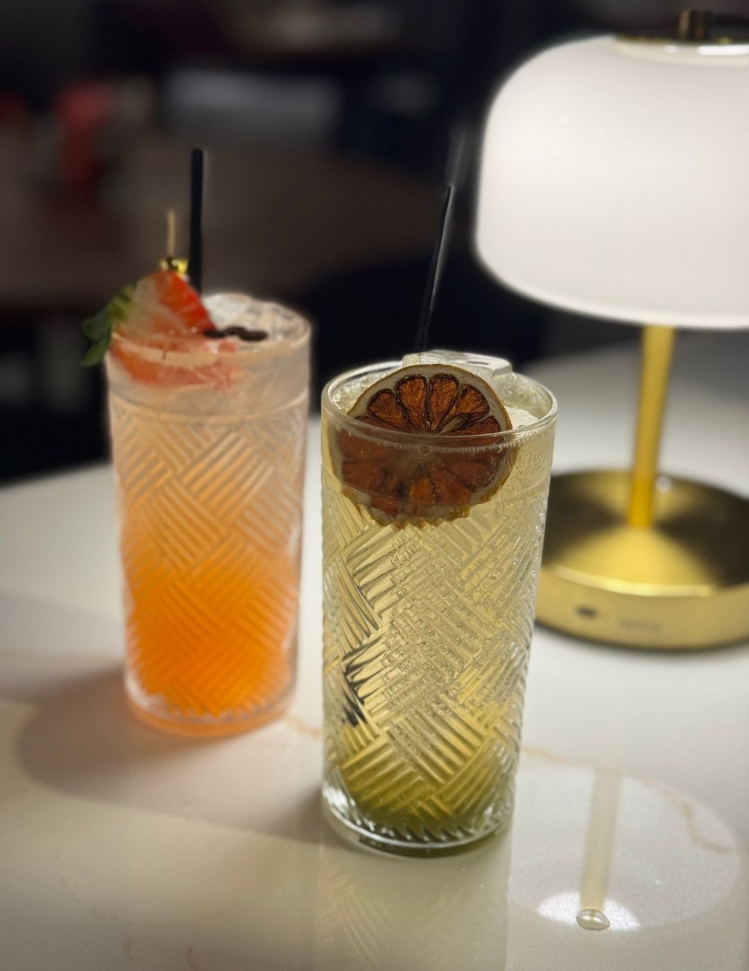 An amber-colored cocktail in a rocks glass with ice and a citrus garnish