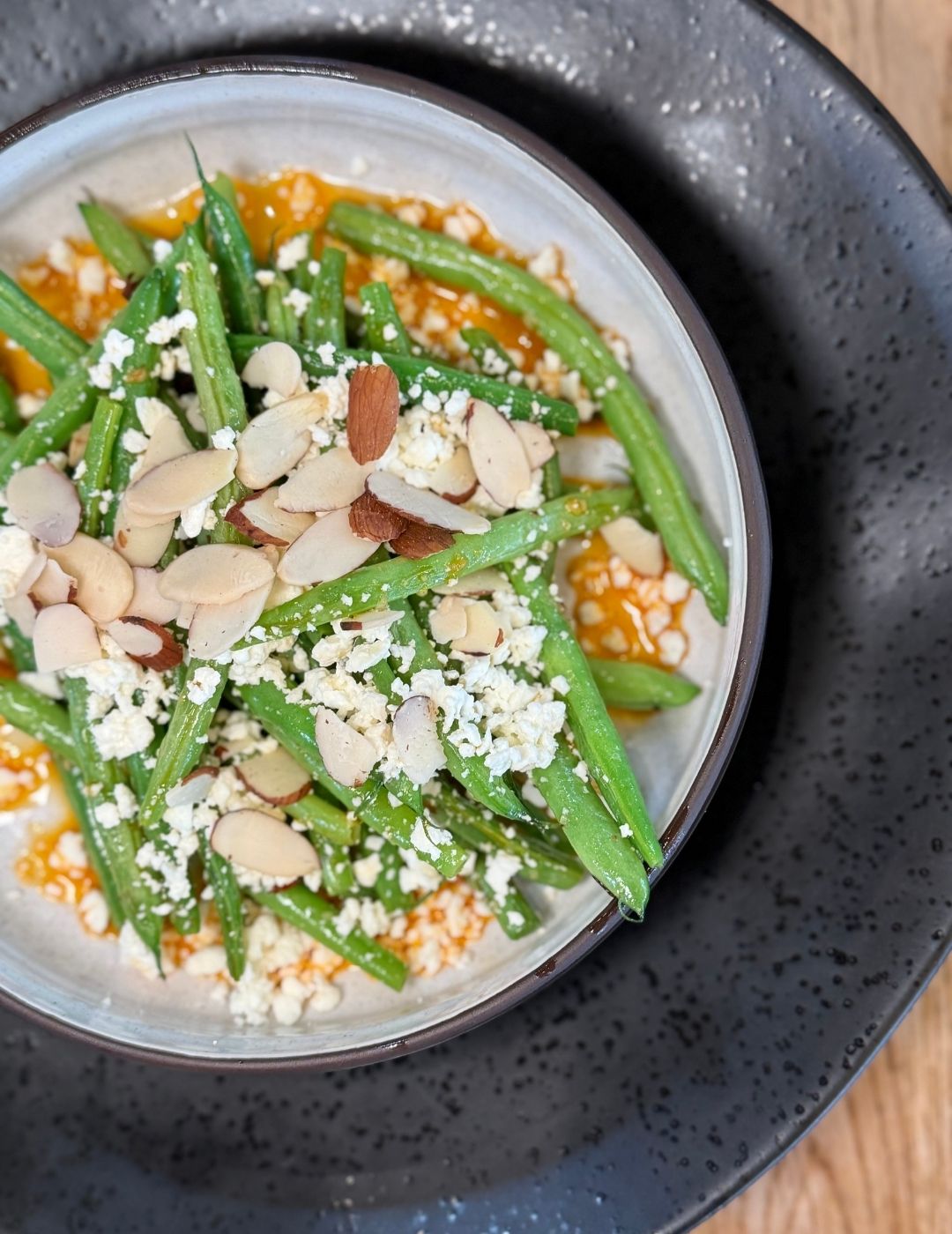 A colorful bowl topped with roasted vegetables, chickpeas, and a drizzle of sauce