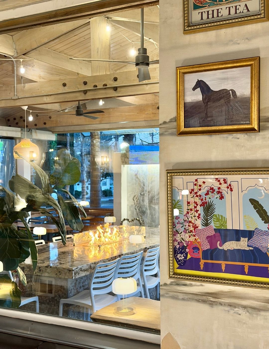 Bright airy restaurant dining room with large windows, framed artwork, and natural light