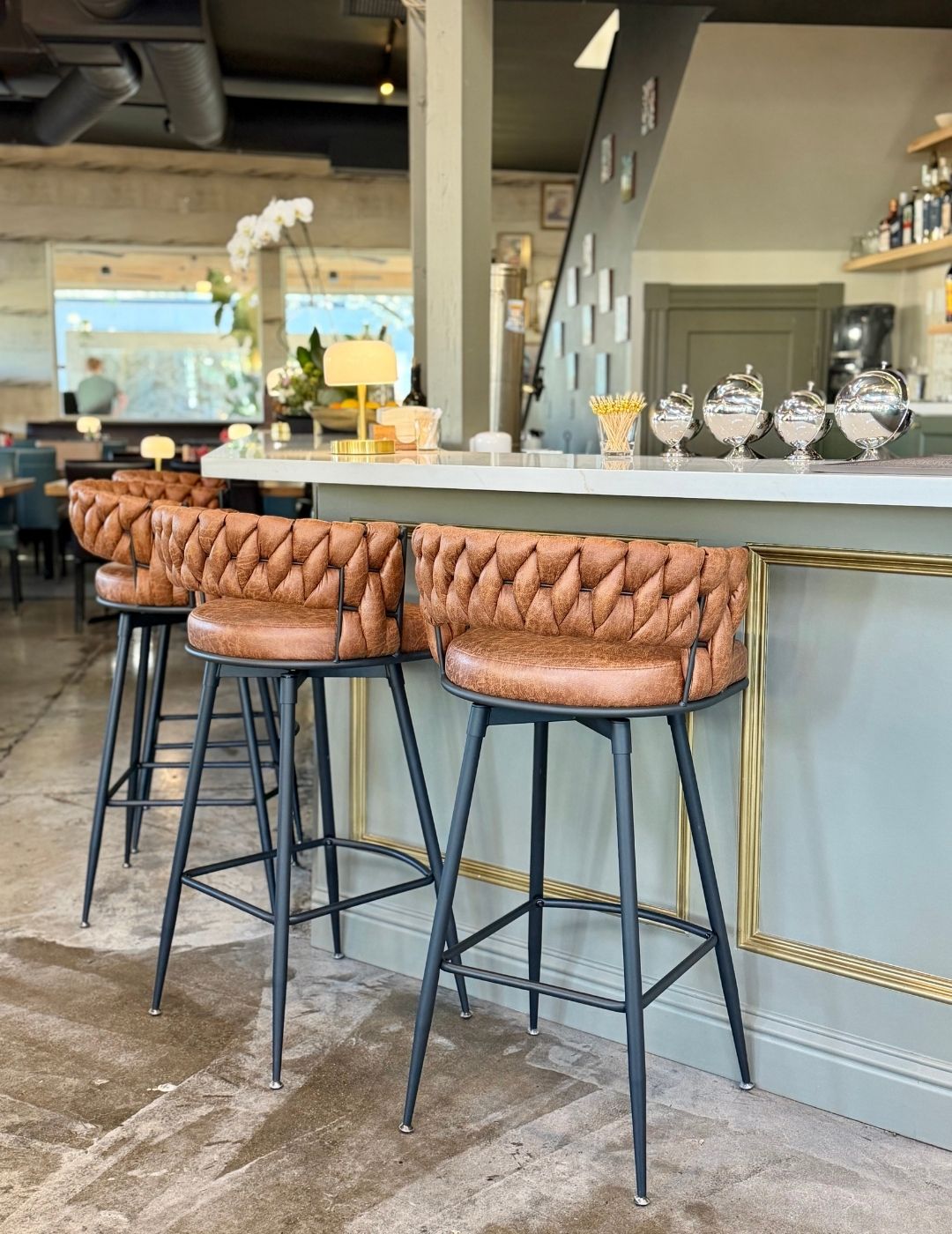 A restaurant bar with stools and pendant lights in a warmly lit interior