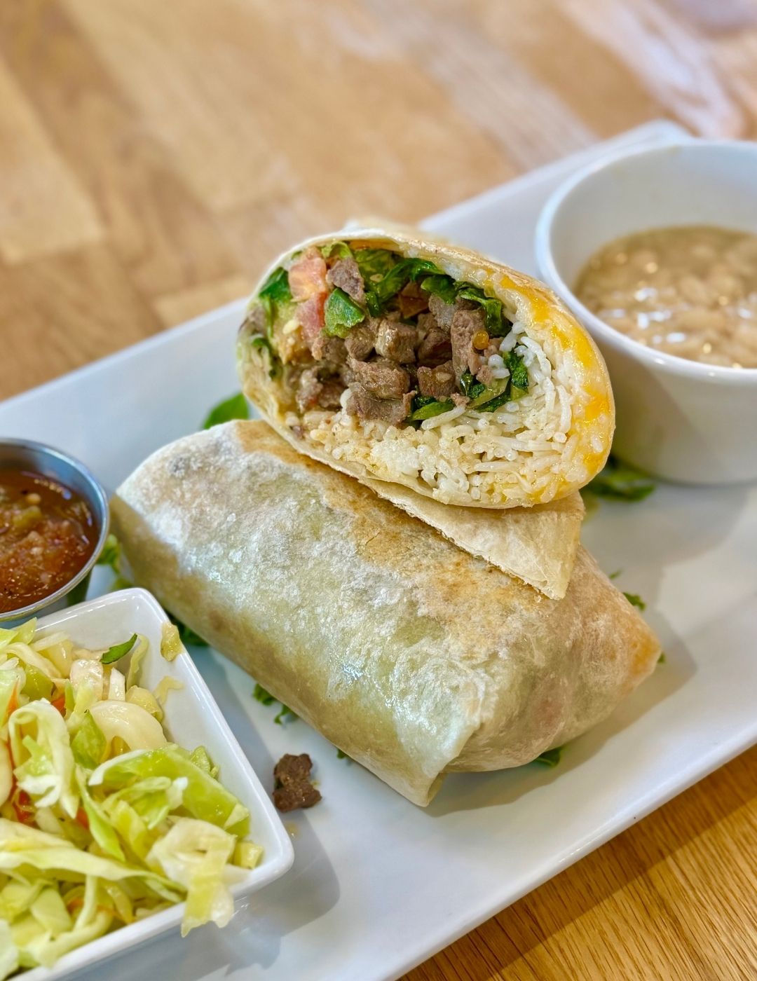 A green wrap or burrito served on plate