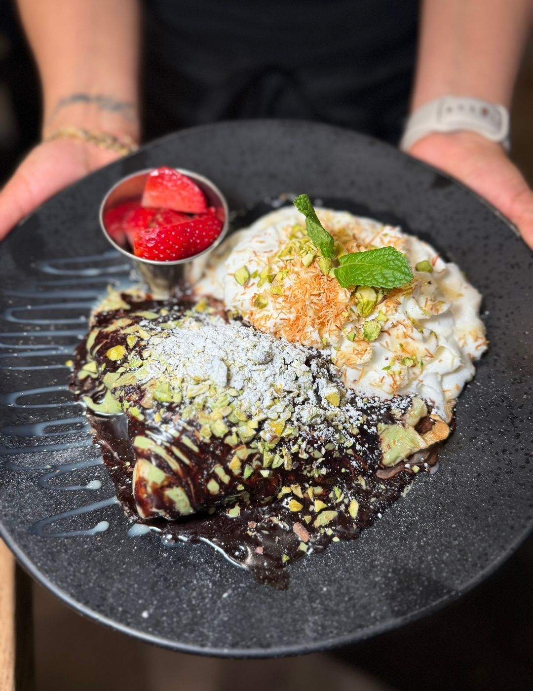 A decorative desert topped with seeds and herbs on a dark surface