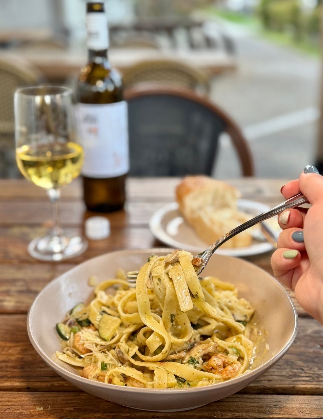 A bowl of pasta with sauce and garnish on a dark surface