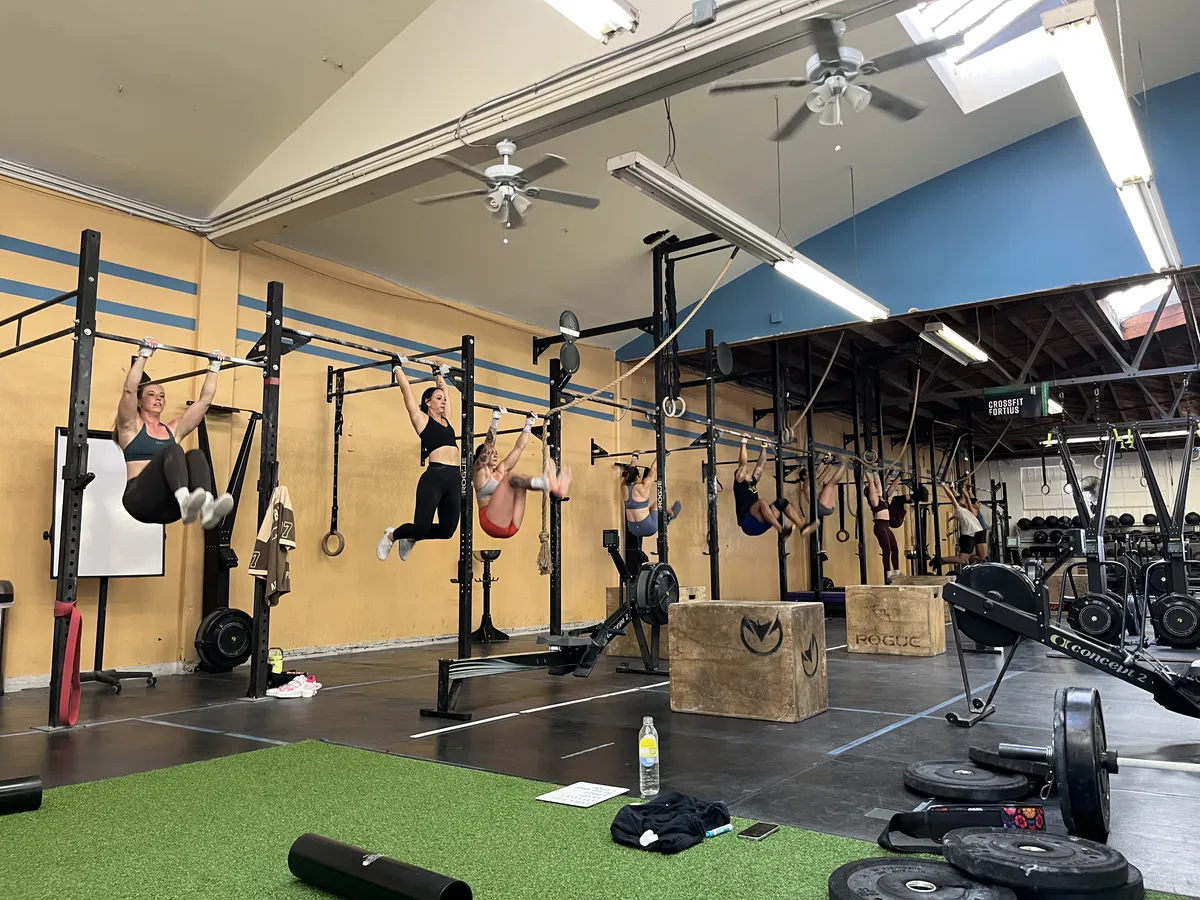 Members practice toes-to-bar on the pull-up rig during a gymnastics class at CrossFit Fortius in Point Loma