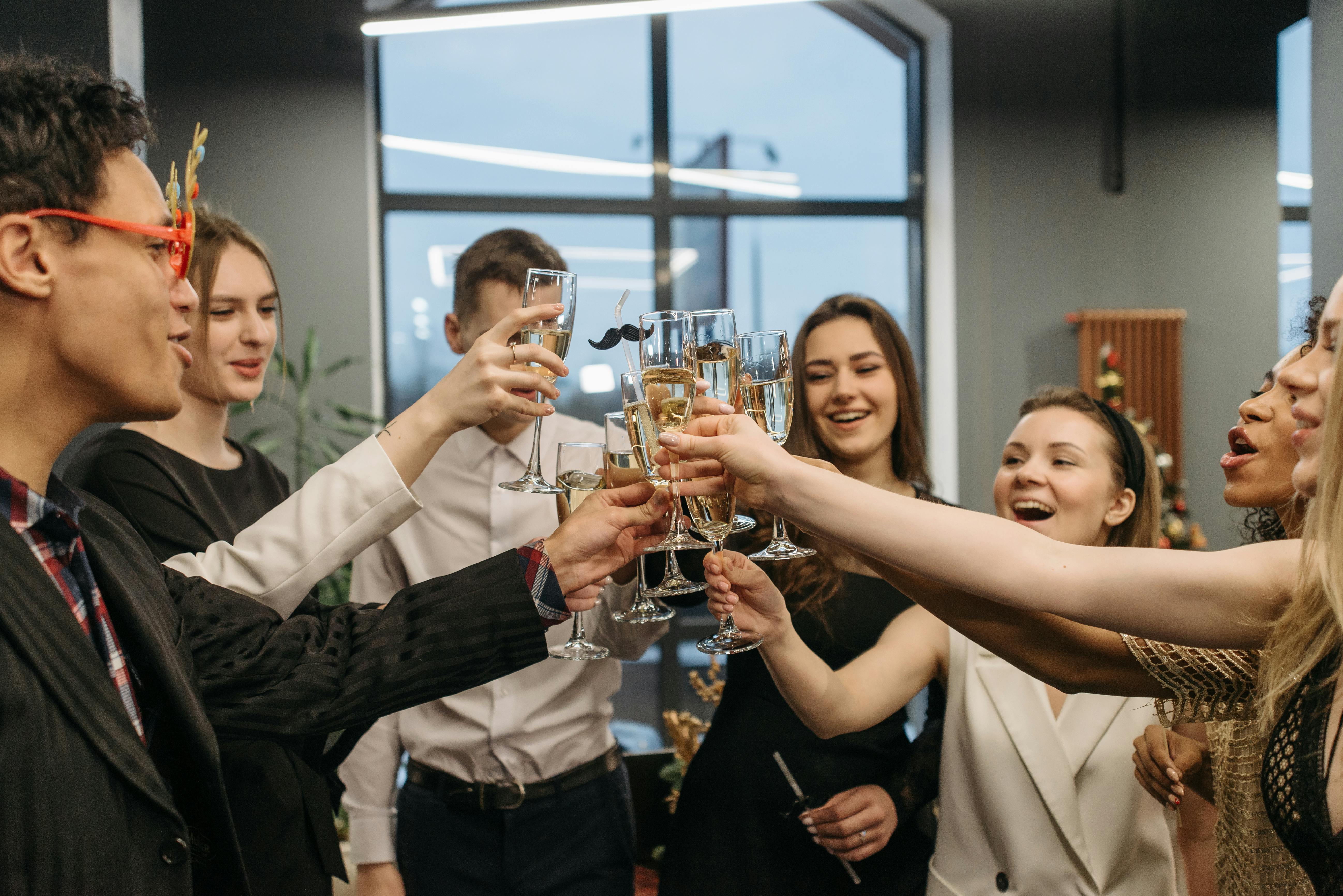 A group of seven party-goers smiling and raising their champagne glasses together.