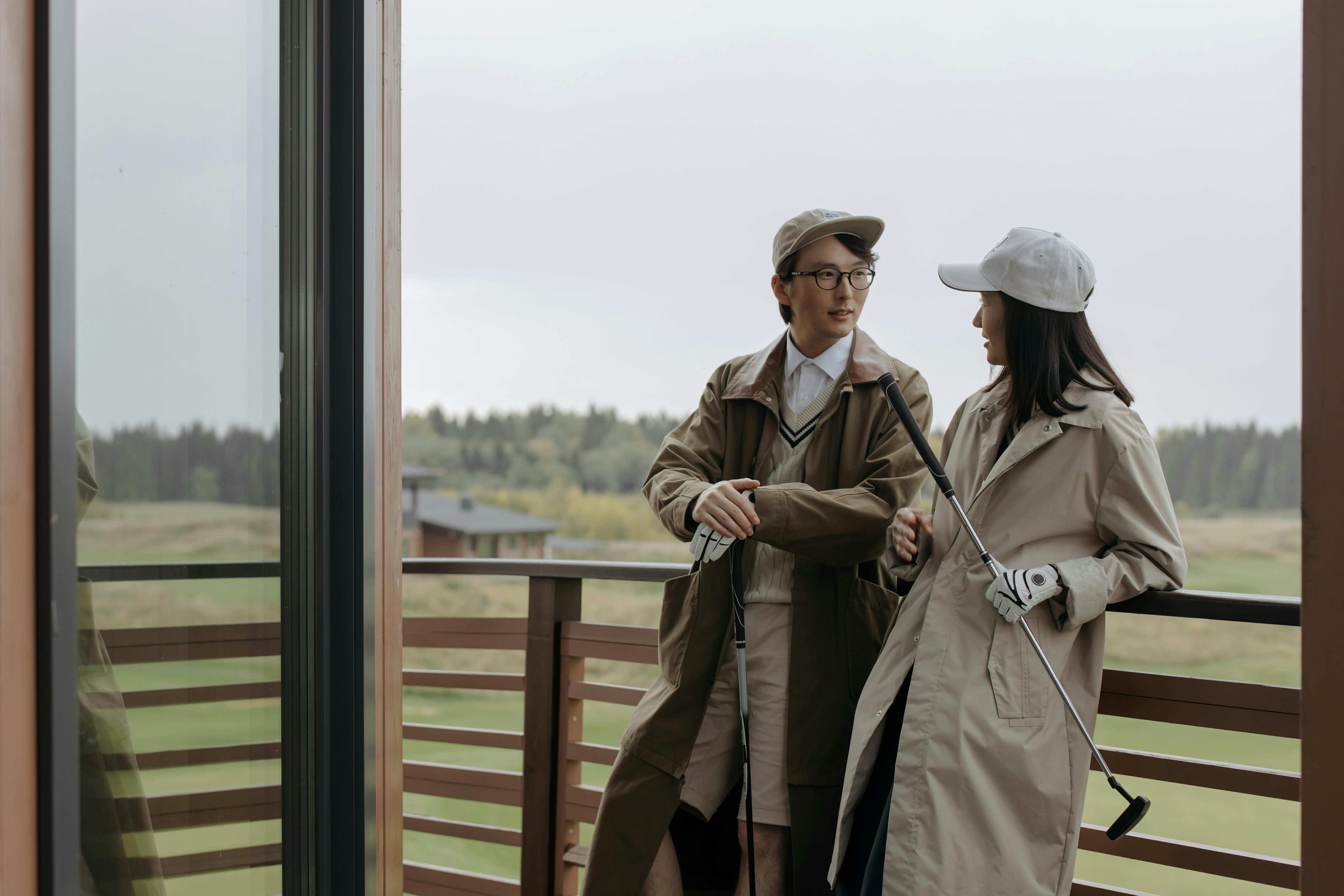 A couple holding golf clubs and talking to each other.