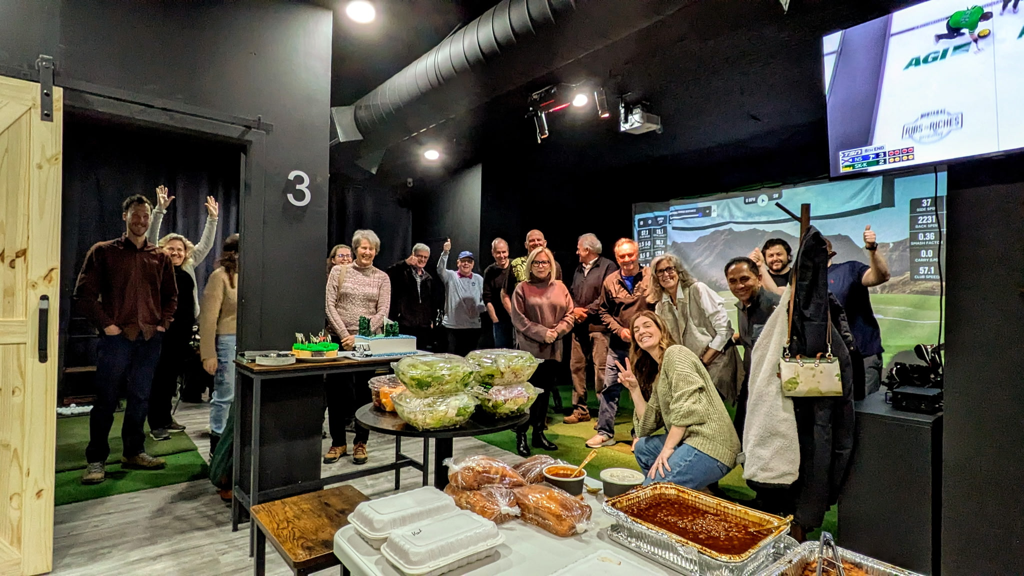 Club X Indoor Golf private party patrons posing for a photo behind tables of food.