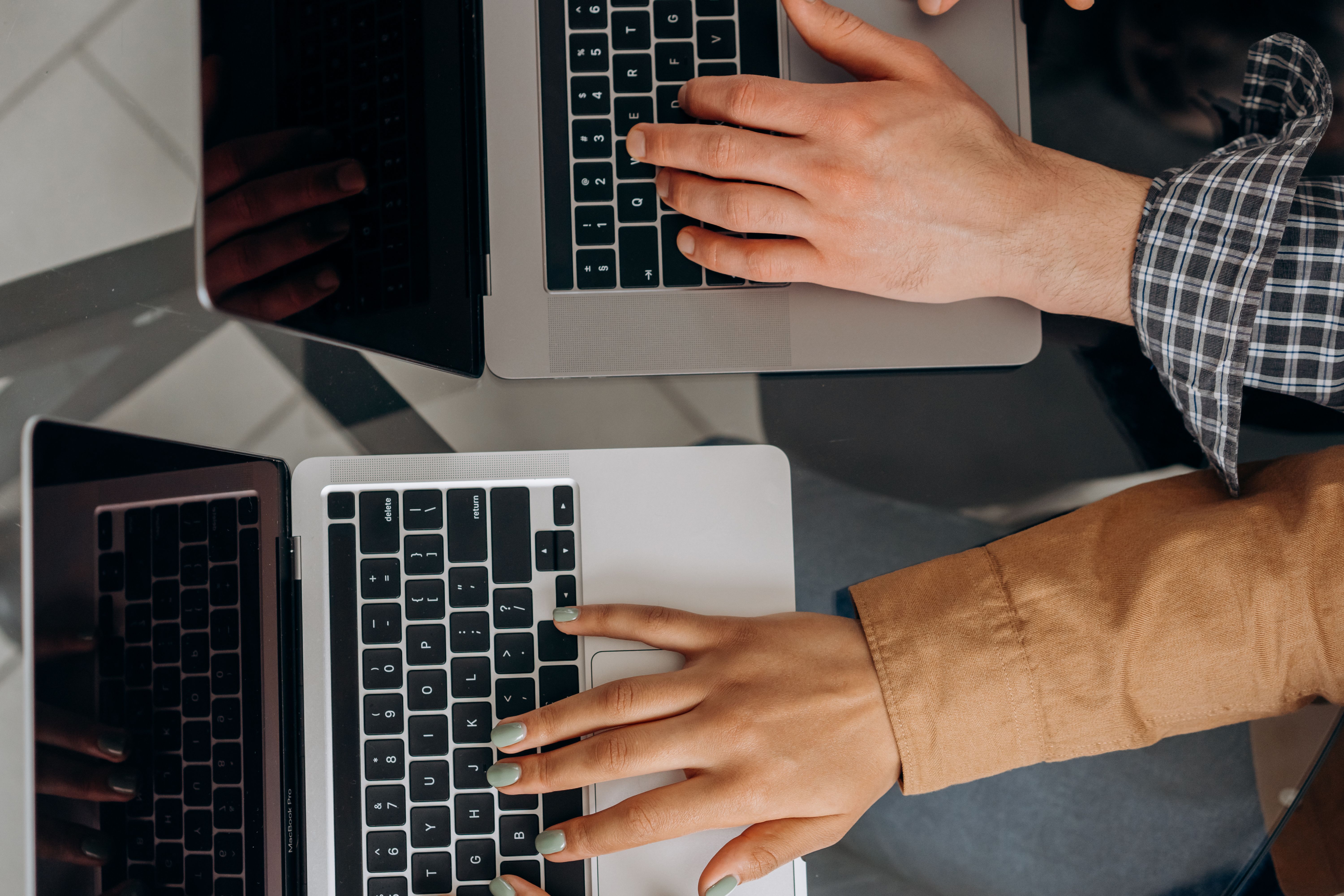 An overhead closeup shot of two people's hand on their laptop