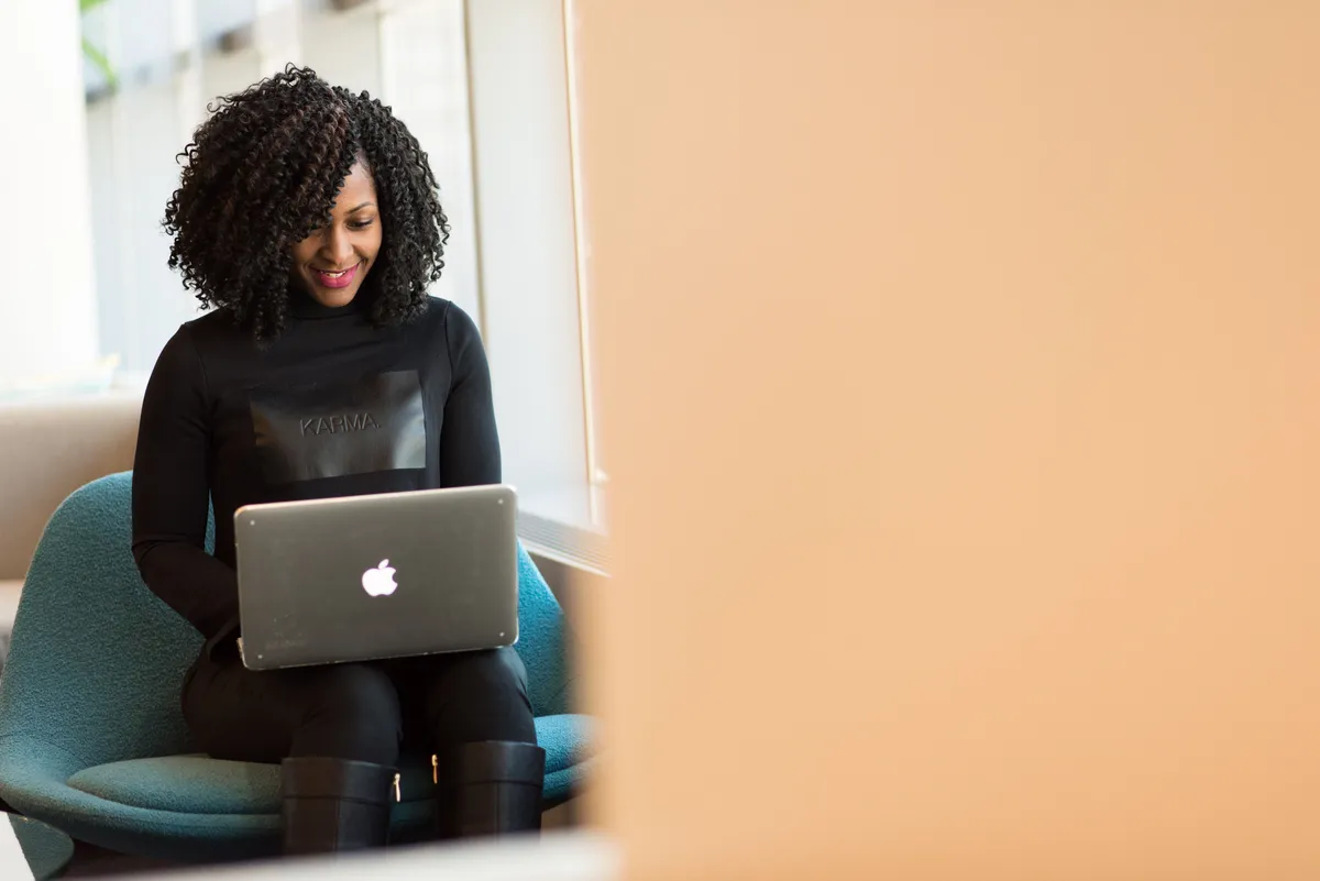 A woman smiling down at a laptop on her lap