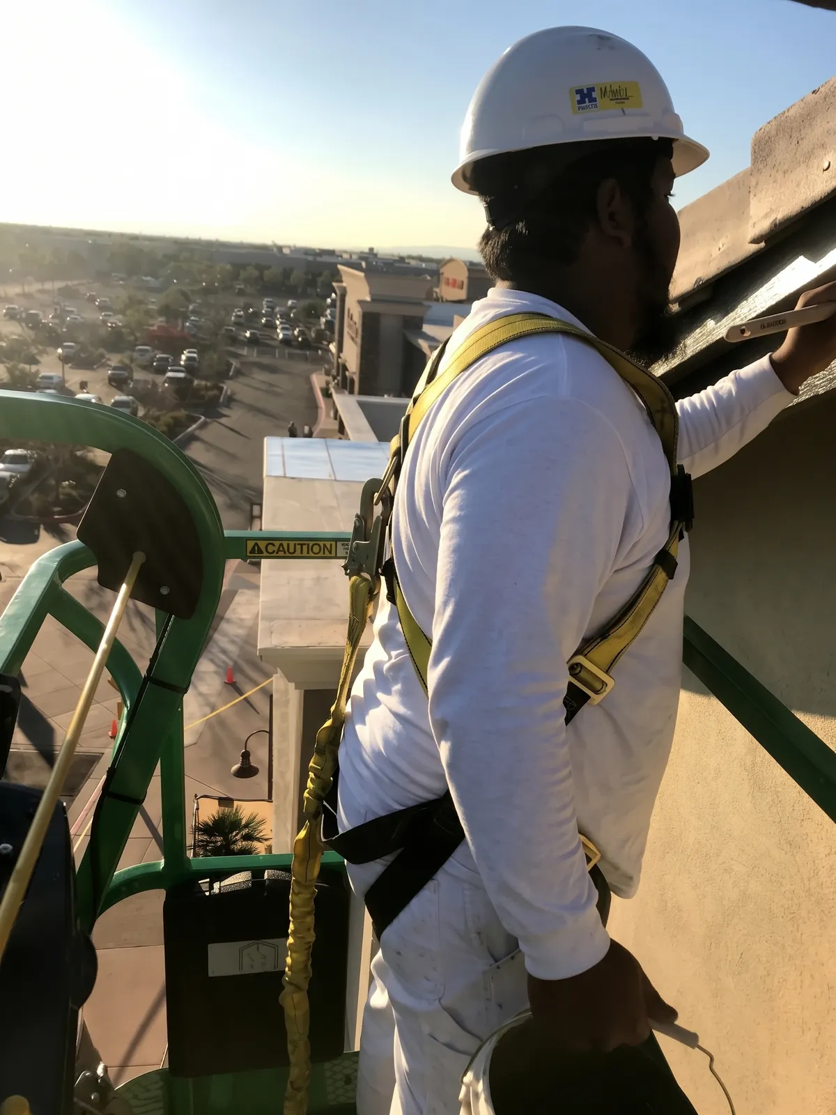 High-reach building facade painting by DL Coatings: precision exterior fascia brush work, boom lift positioning, and complete safety fall protection.