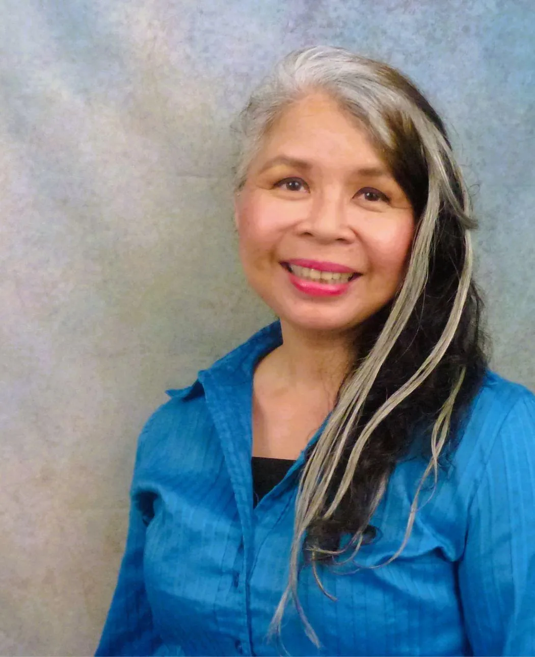 Headshot of a woman with salt and pepper hair, smiling at the camera.