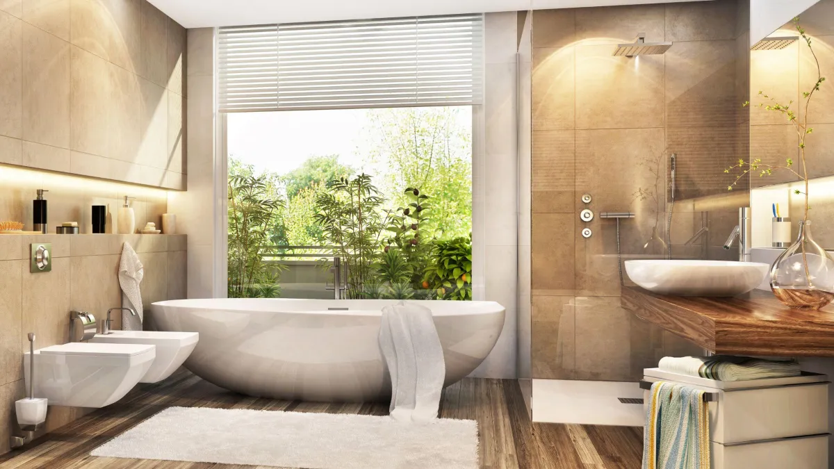 Modern bathroom oasis with a neutral palette, featuring a freestanding oval bathtub on a wood-patterned floor. A wall-mounted toilet and a sleek basin sit atop custom wooden cabinetry. The space is bathed in natural light streaming through a window with a view of lush greenery, complemented by tan tiles and a glass-enclosed walk-in shower with a rainfall showerhead. The peaceful ambiance is accented with soft textiles and a touch of green from an indoor plant.