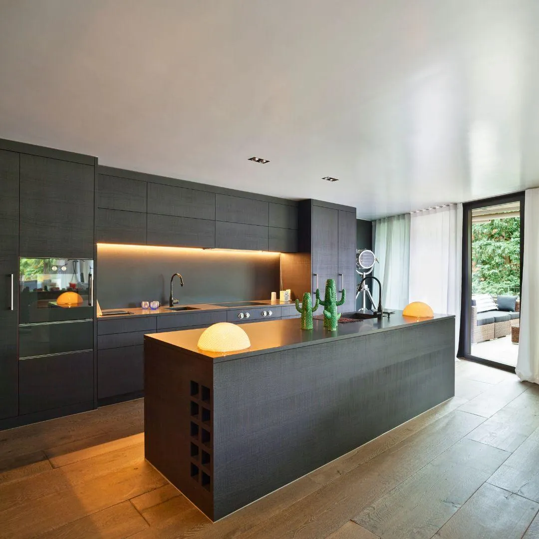 "Sleek modern kitchen with dark wood cabinets, illuminated under-cabinet lighting, and a spacious island by Elci Cabinets and Floors