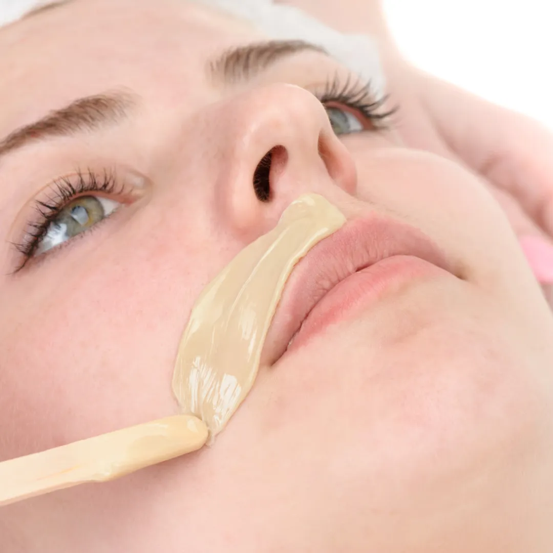 Esthetician removing wax from a client's upper lip during facial hair removal