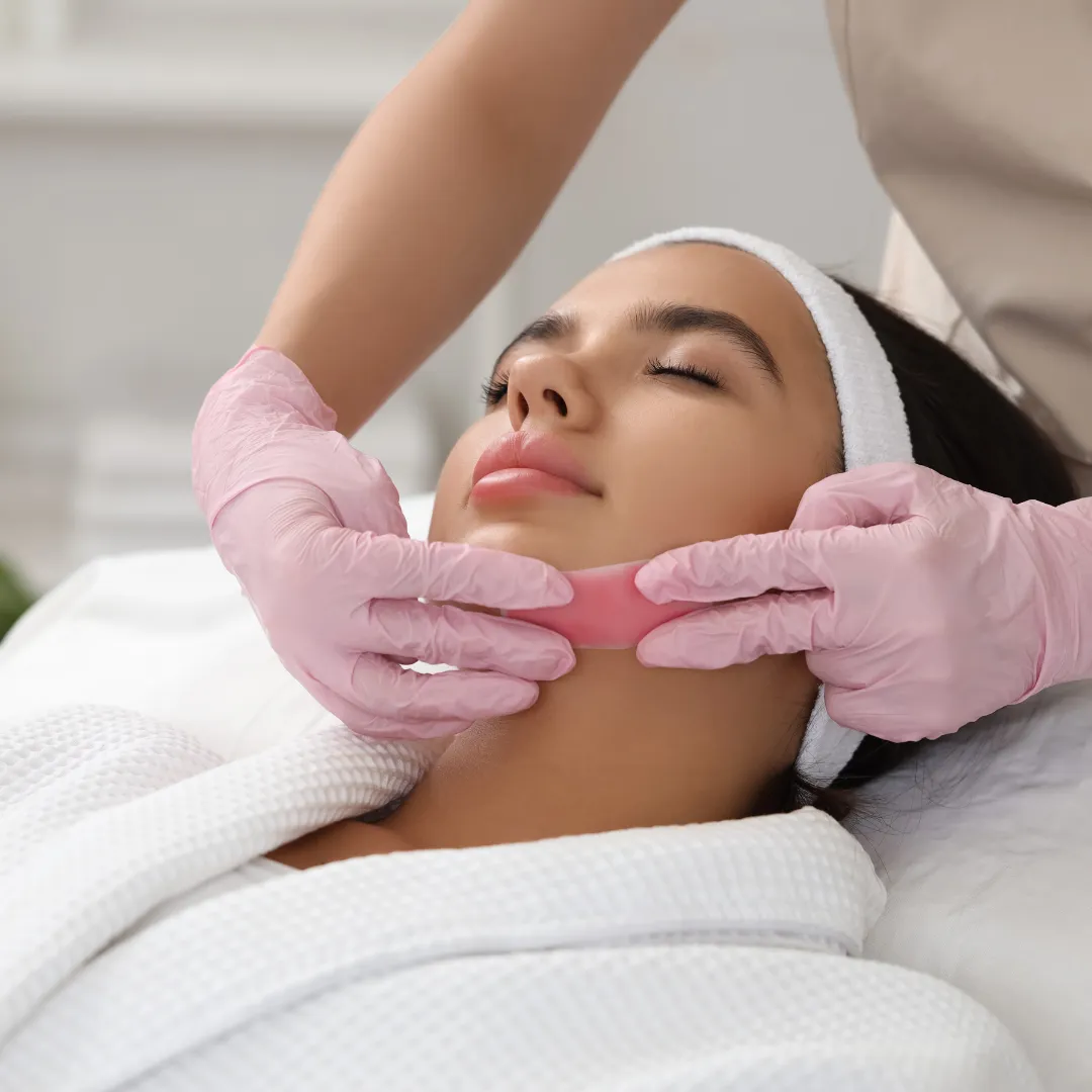 Female client undergoing chin hair removal with wax at a spa
