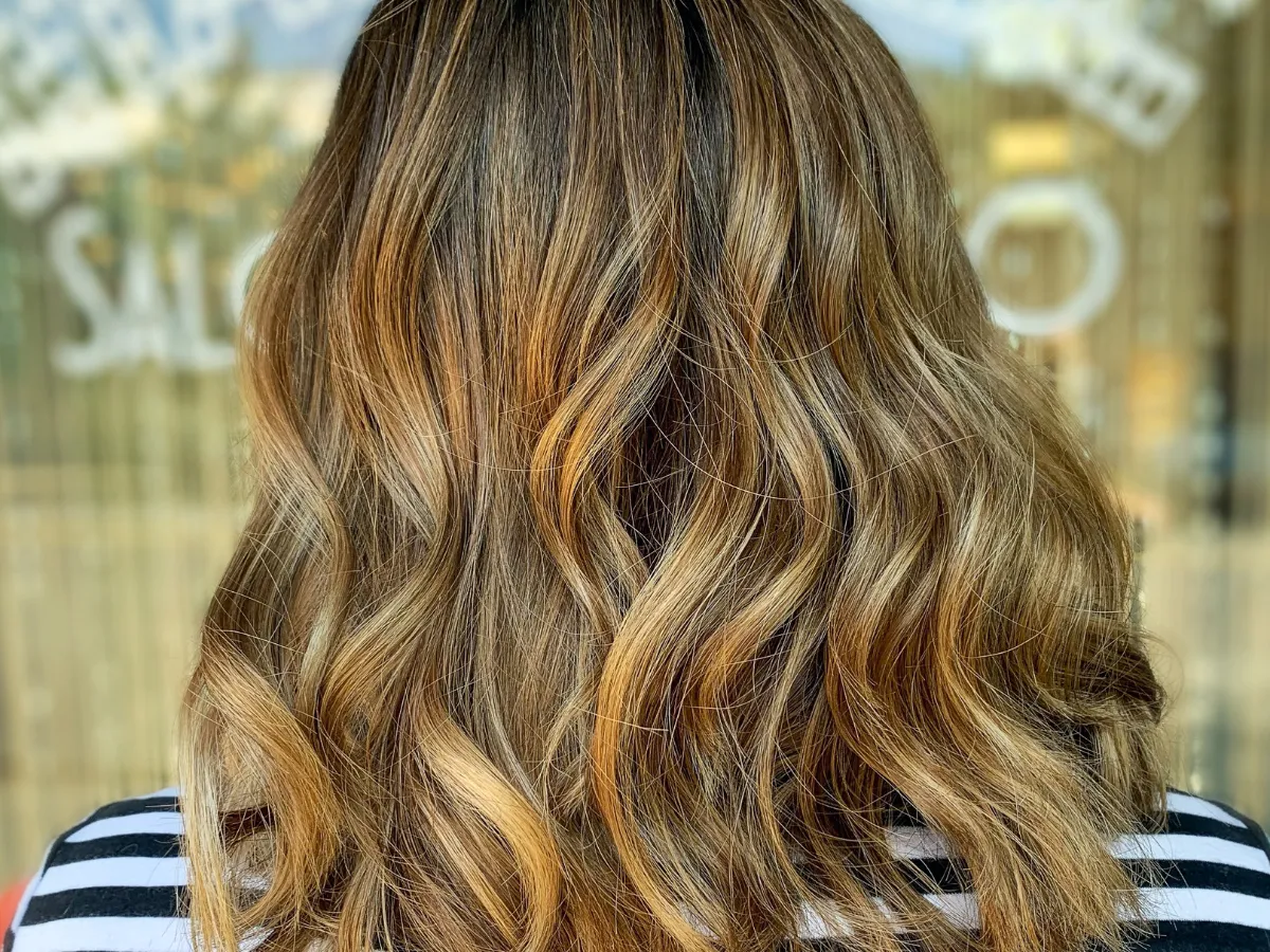 Light brown hair in curls demonstrating full highlights throughout the hair.