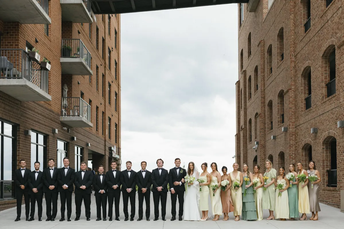 couple-and-wedding-party-posing-outside-with-historic-architecture