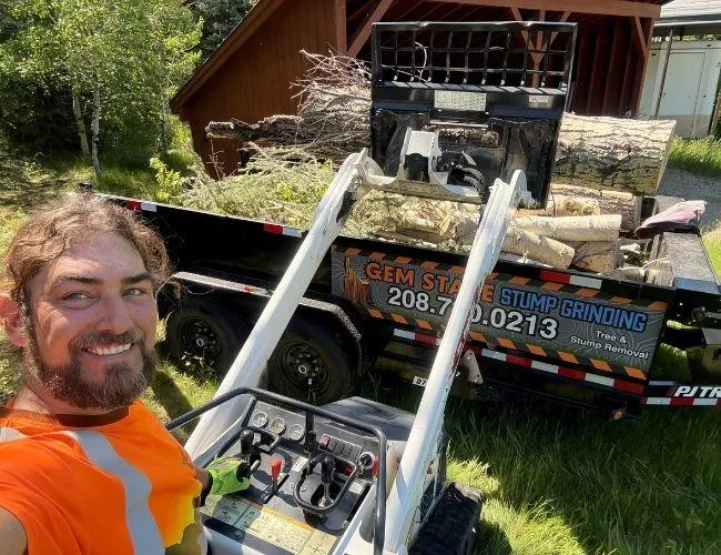 Gem State Tree Service and Stump Grinding crew loading cut logs into branded truck during tree removal project in Idaho