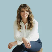 Dana Collins headshot. A light brown haired woman in a white blouse sitting and smiling.