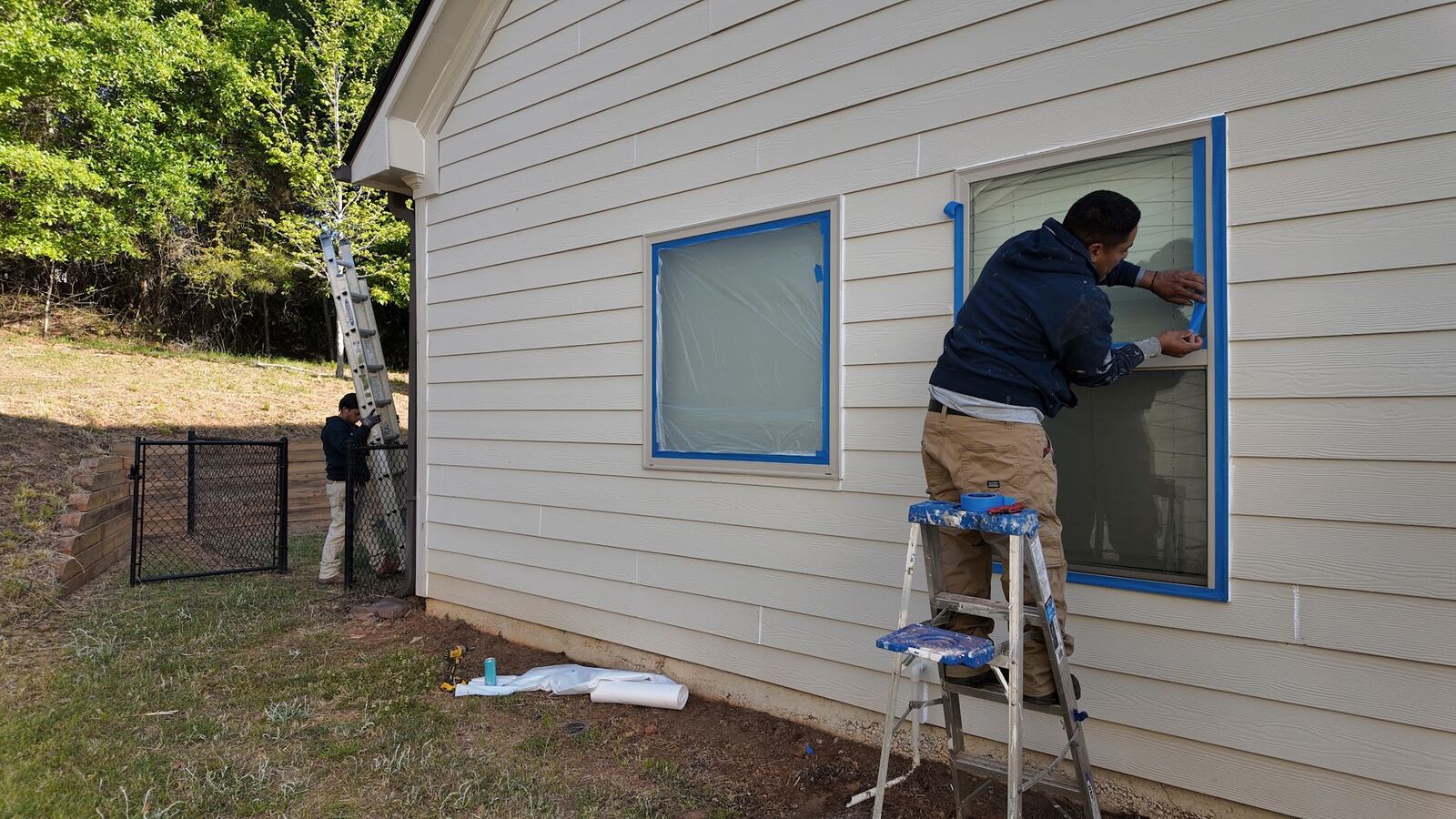 BrightBrush crew masking windows before painting an exterior