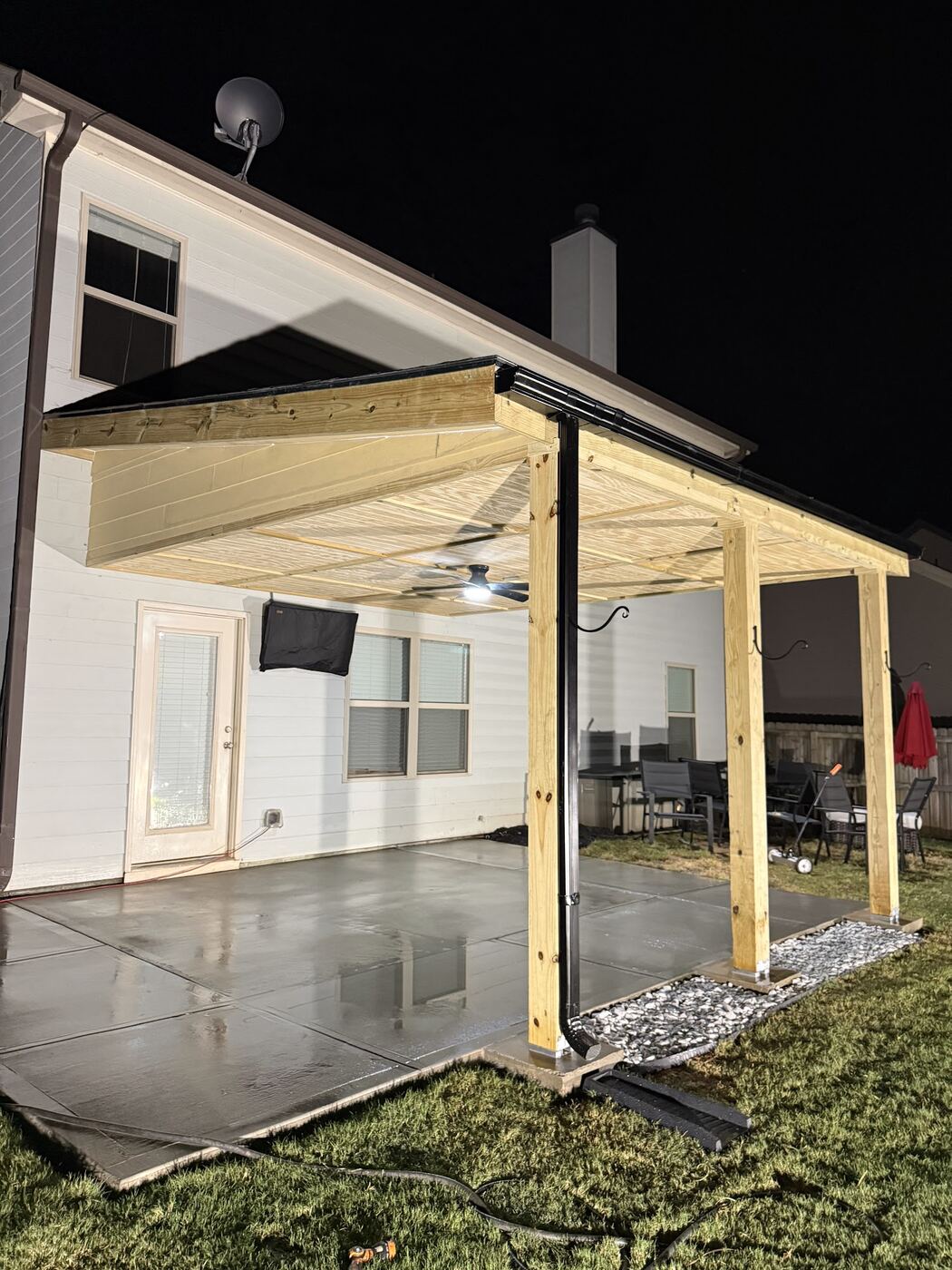 New covered patio with concrete slab, lit at night