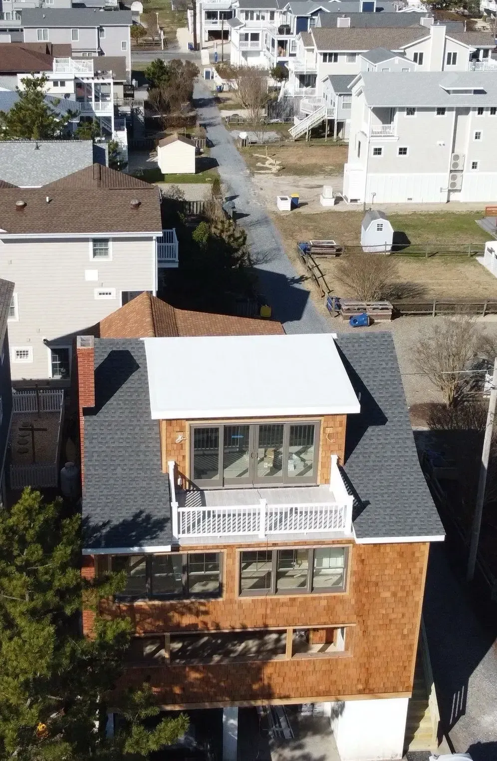 White low-slope roof section installed on a multi-story home off the beach