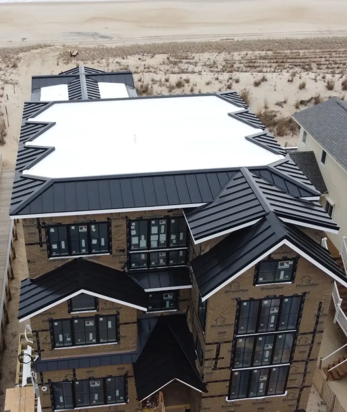 Flat roof installation sections integrated with a multi-story residential roof on the beach