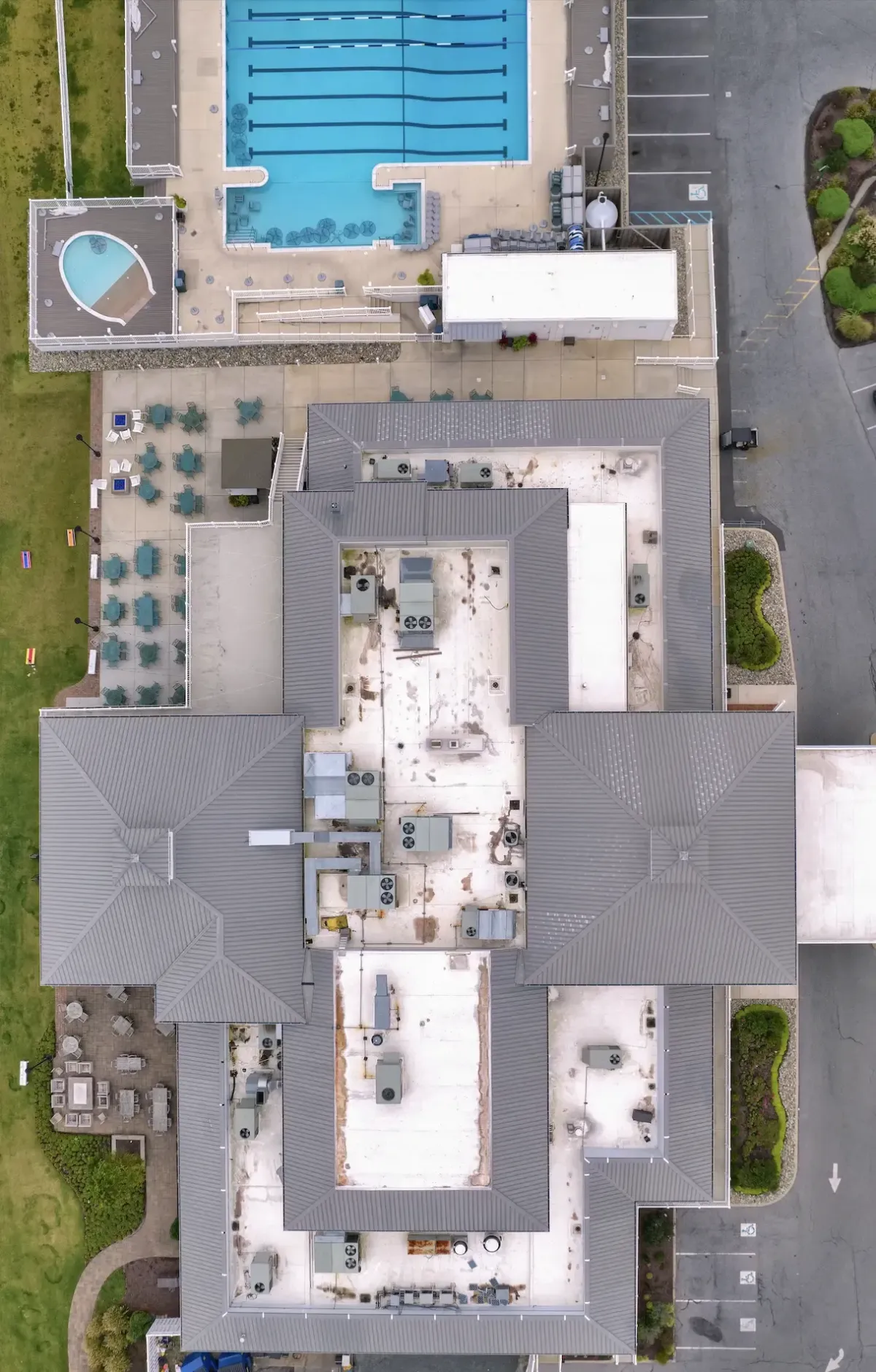 Overhead view of a commercial flat roof with rooftop equipment and surrounding parking areas