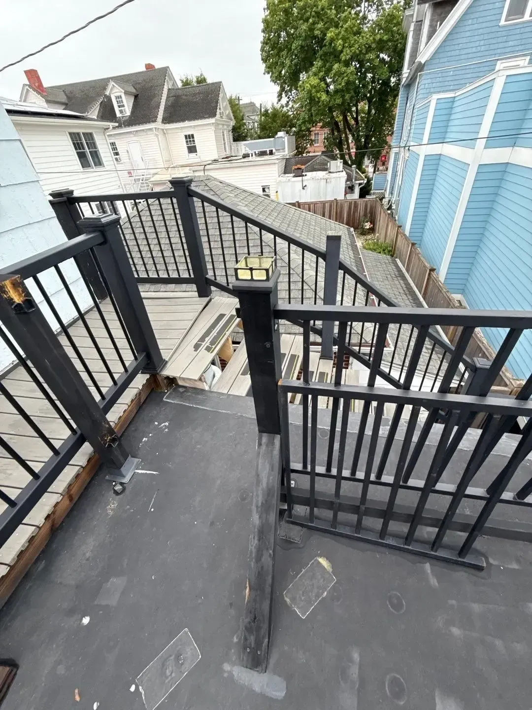 Low-slope roof repair area beside exterior stairs and railings