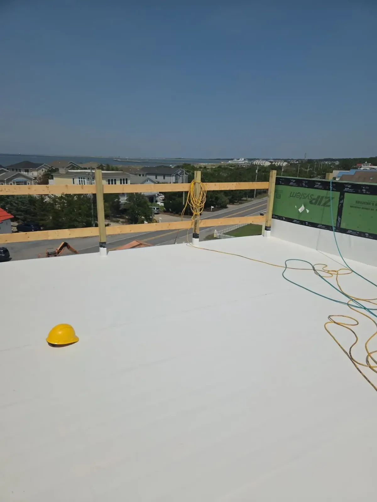 White-coated commercial flat roof with perimeter railing and rooftop penetrations in Lewes