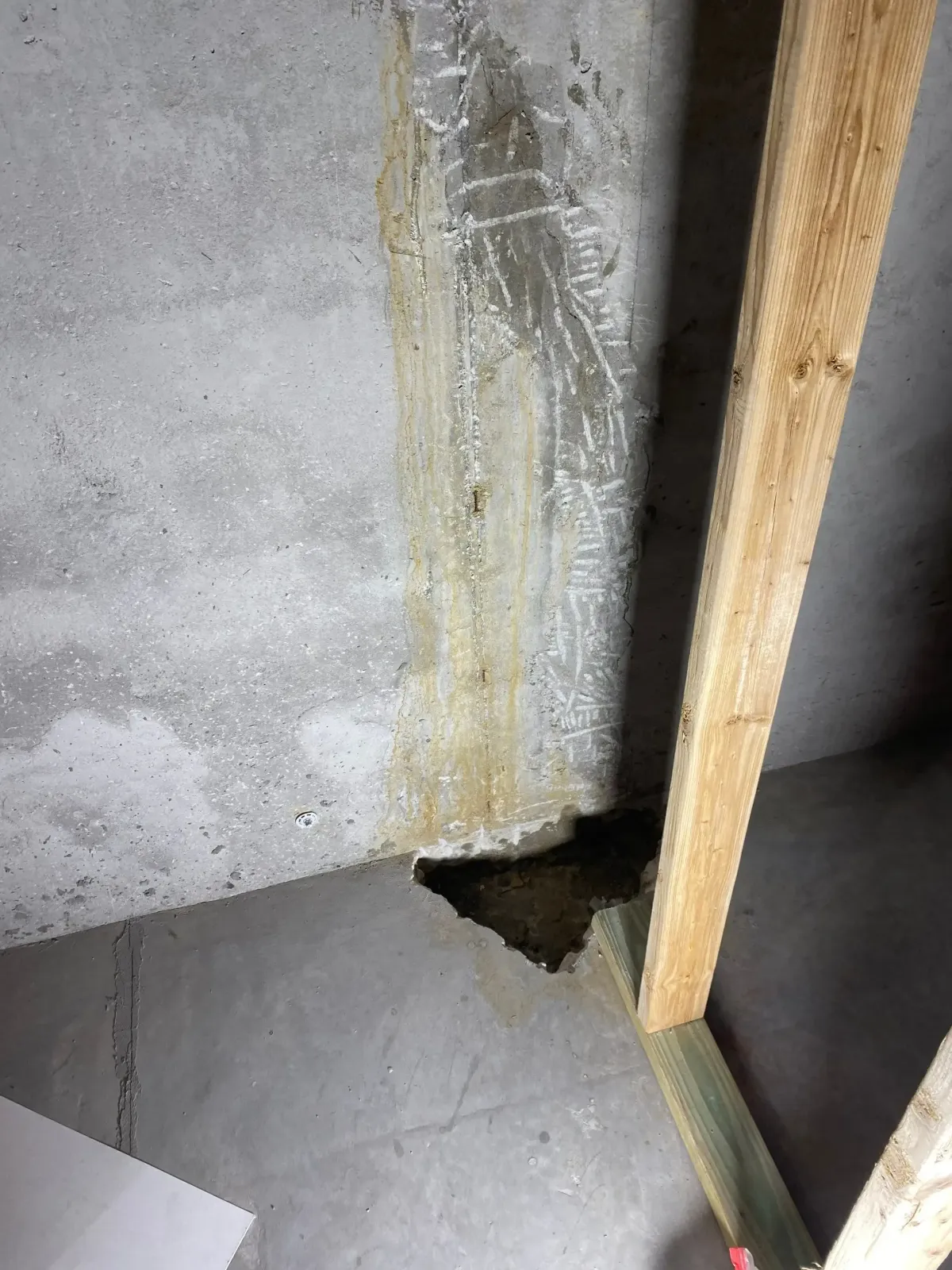 Water staining at a concrete wall-and-floor joint beside exposed wood framing
