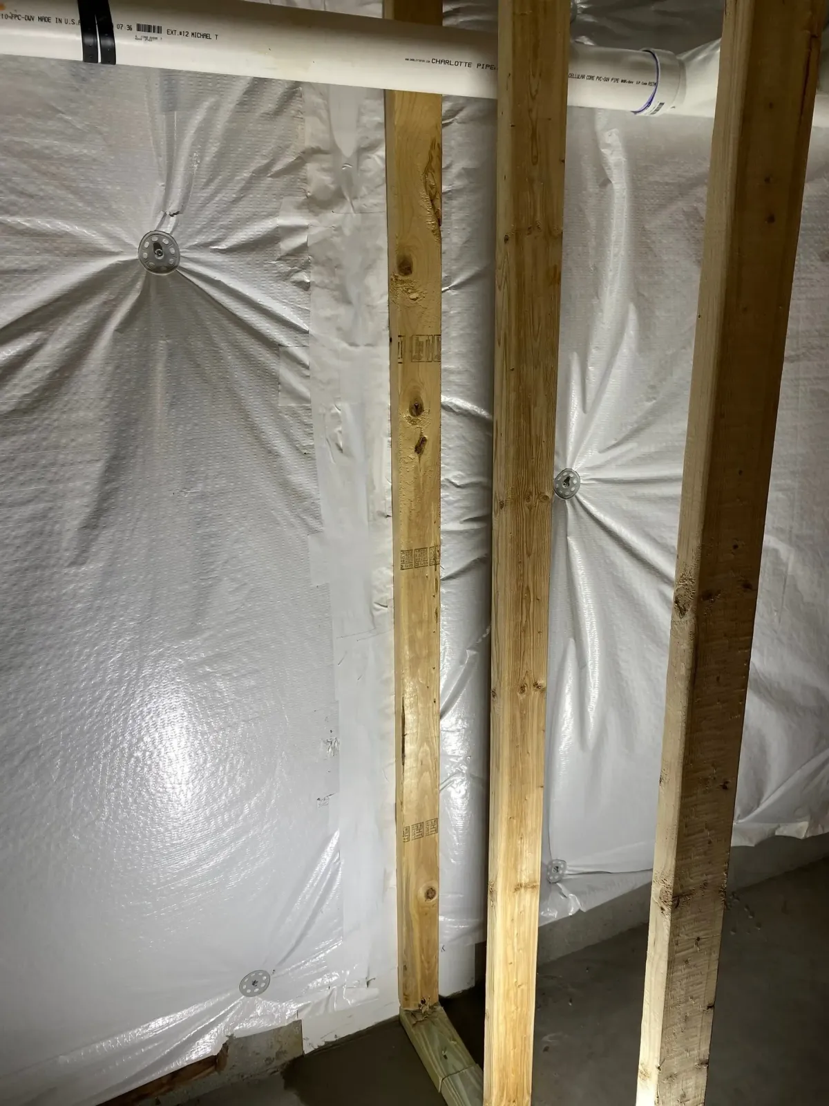 Crawl-space wall with plastic sheeting and exposed wood framing