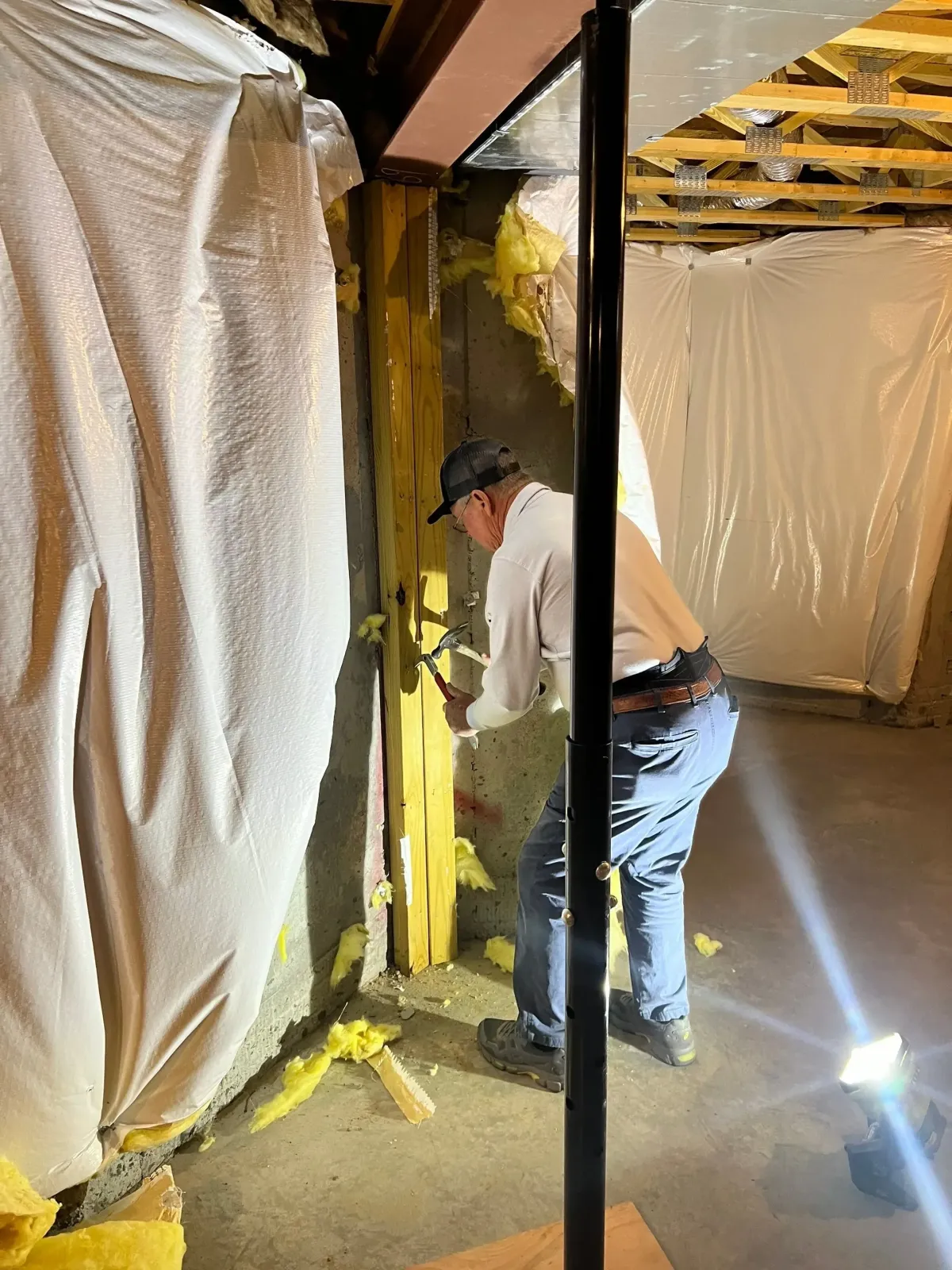 Platinum Roofs working inside a crawl space with plastic sheeting and exposed framing