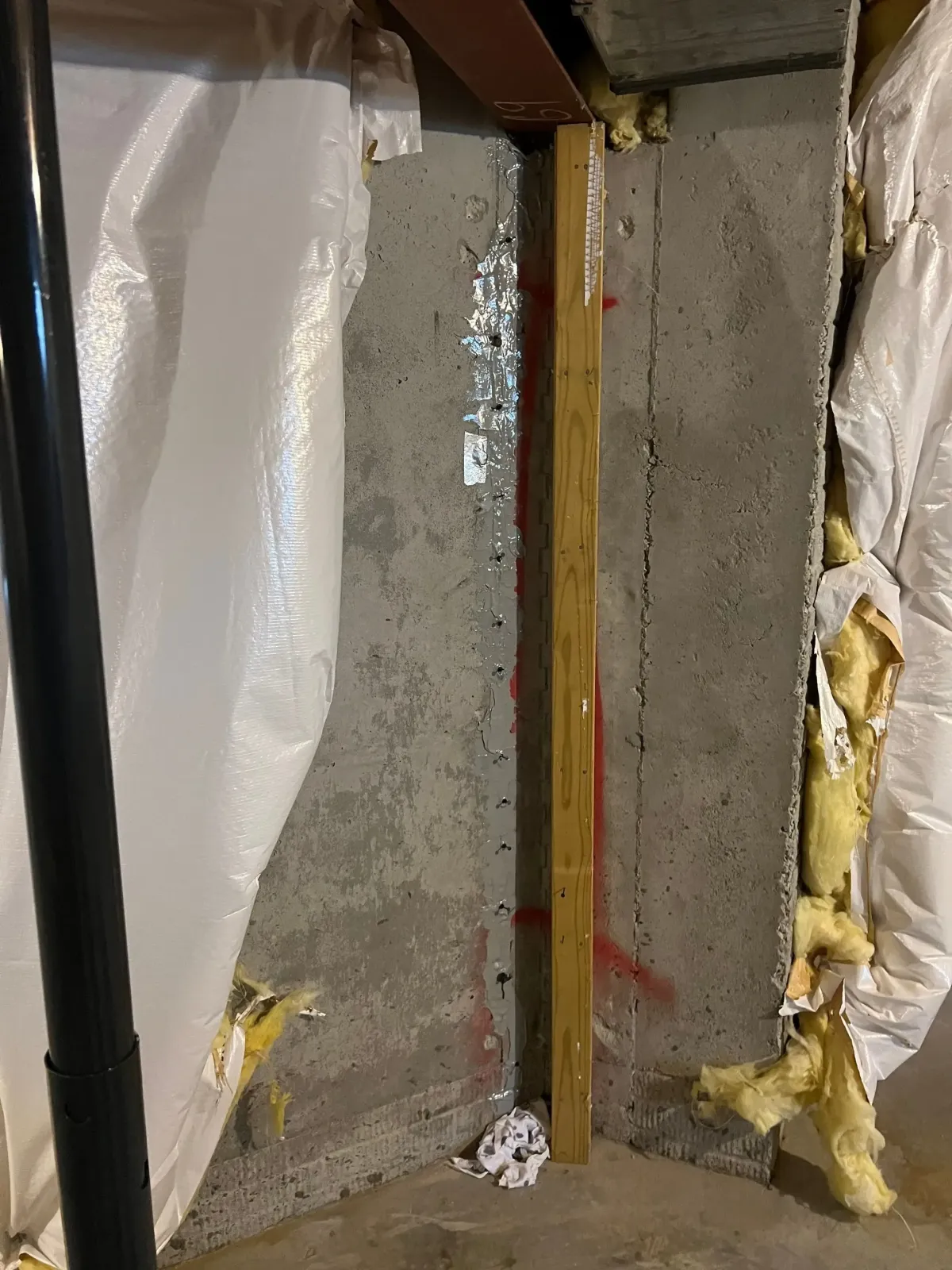 Exposed concrete foundation wall and framing prepared for leak remediation