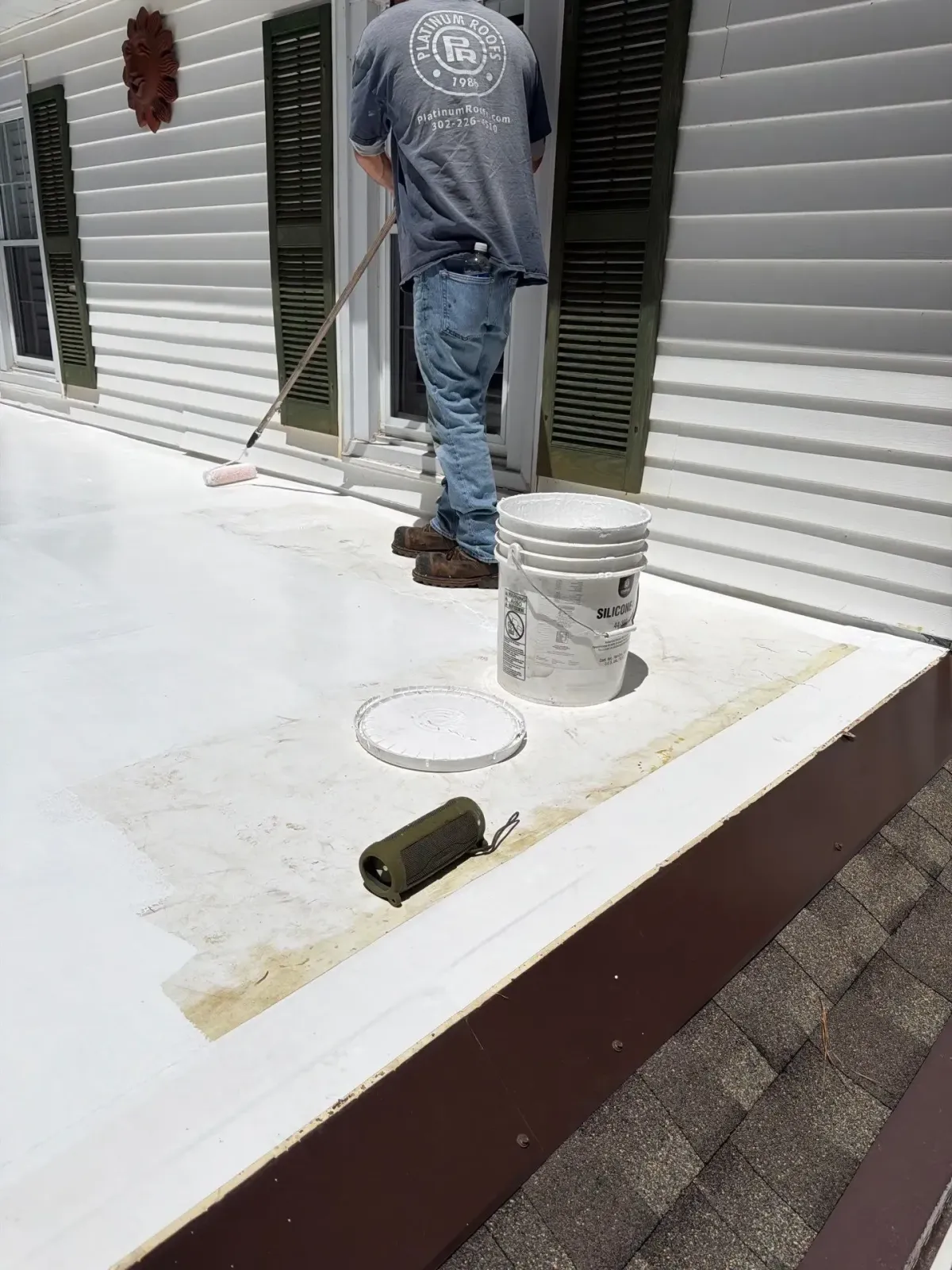 Platinum Roofs team member inspecting a white low-slope roof and wall transition for water intrusion