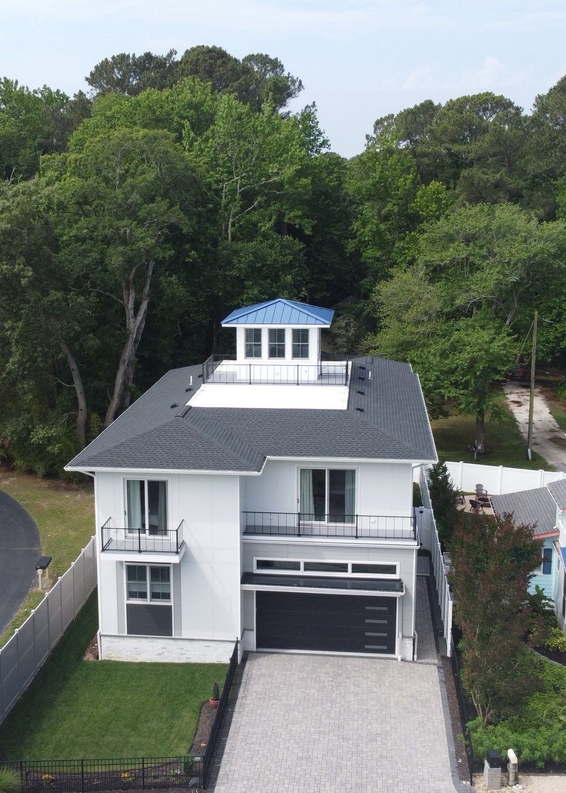 Modern coastal home with dark shingle roofing and a blue metal cupola roof