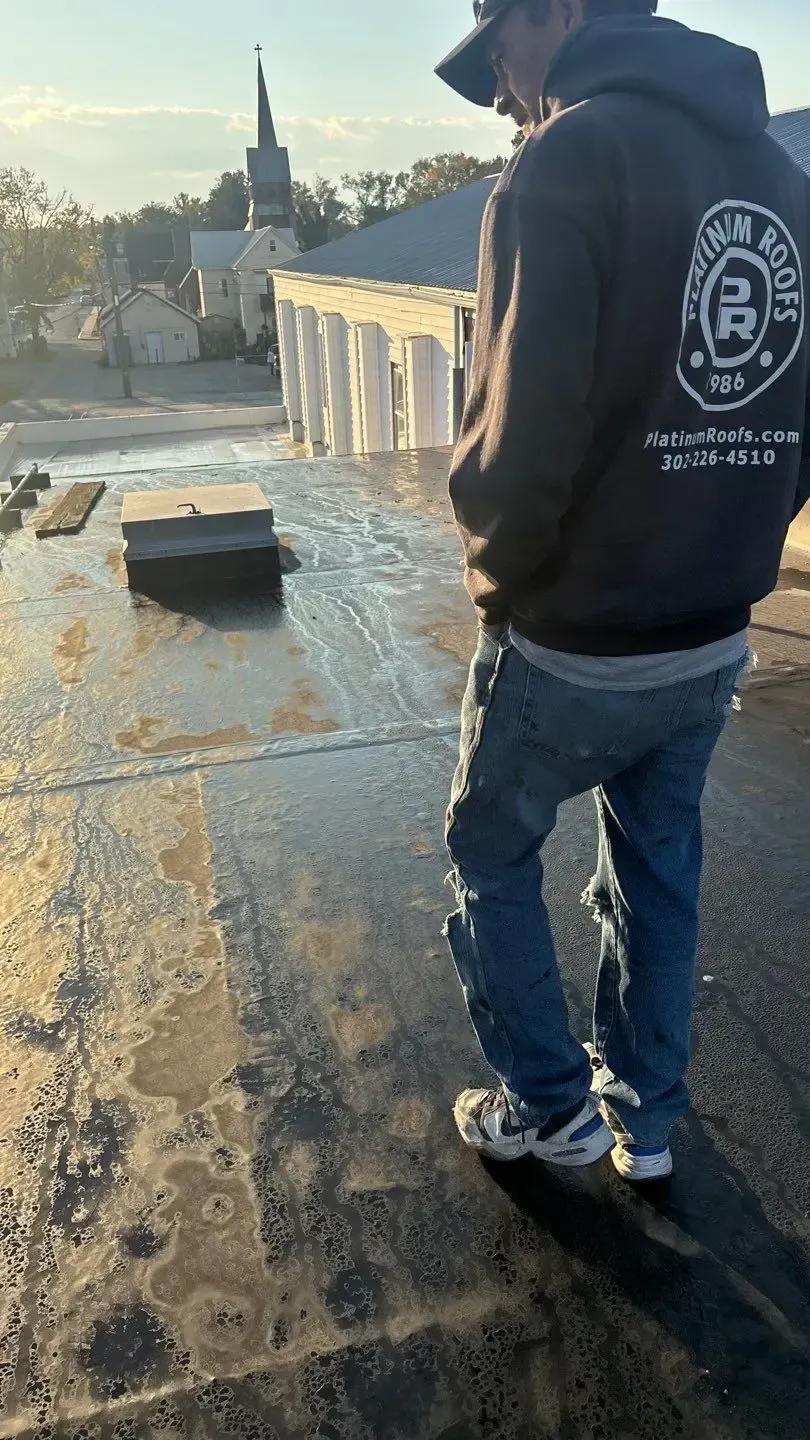 Platinum Roofs technician inspecting a flat commercial roof at 136 East Market Street in Georgetown, Delaware.