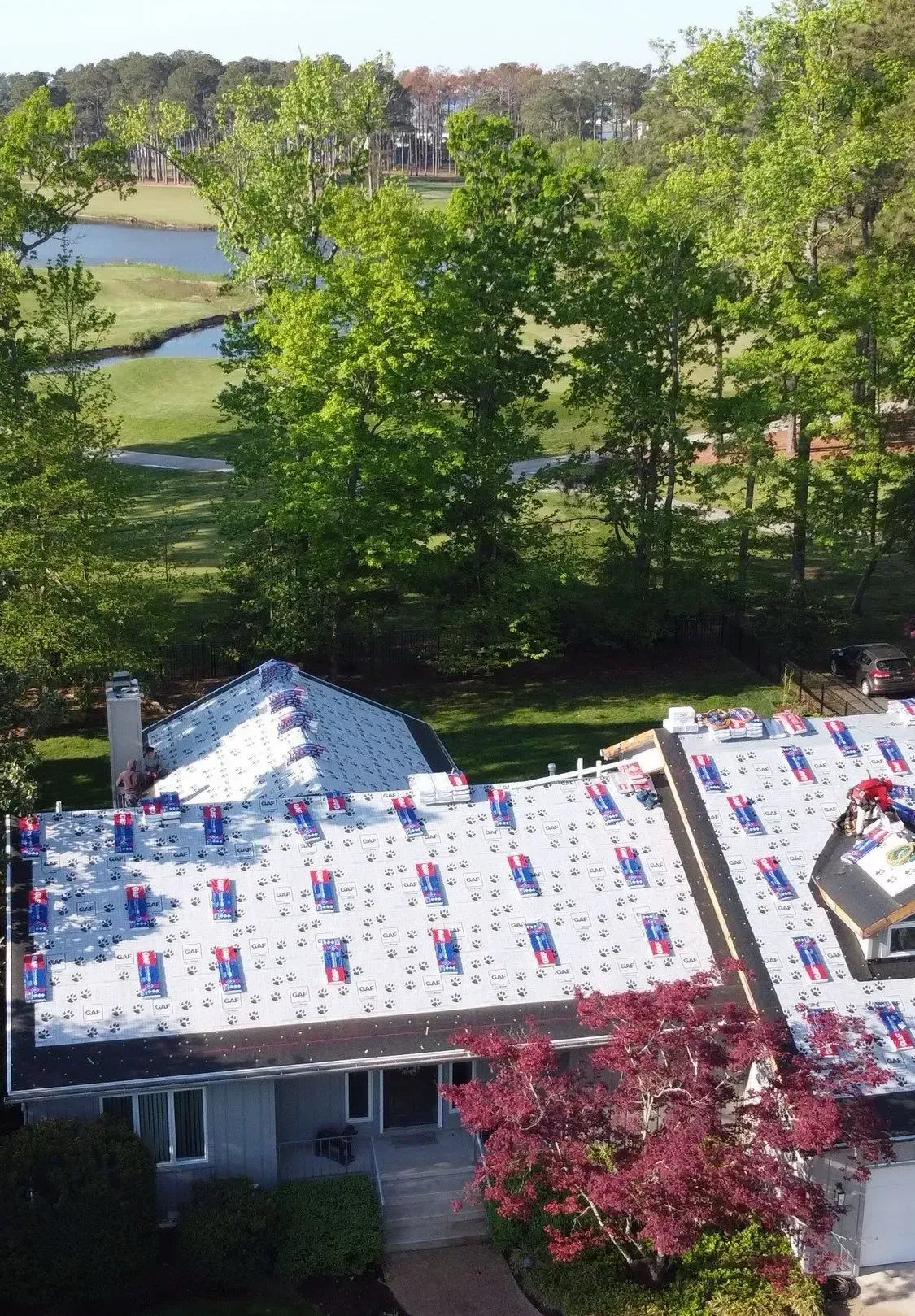 Aerial view of a residential roof covered with patterned underlayment during a roofing installation.