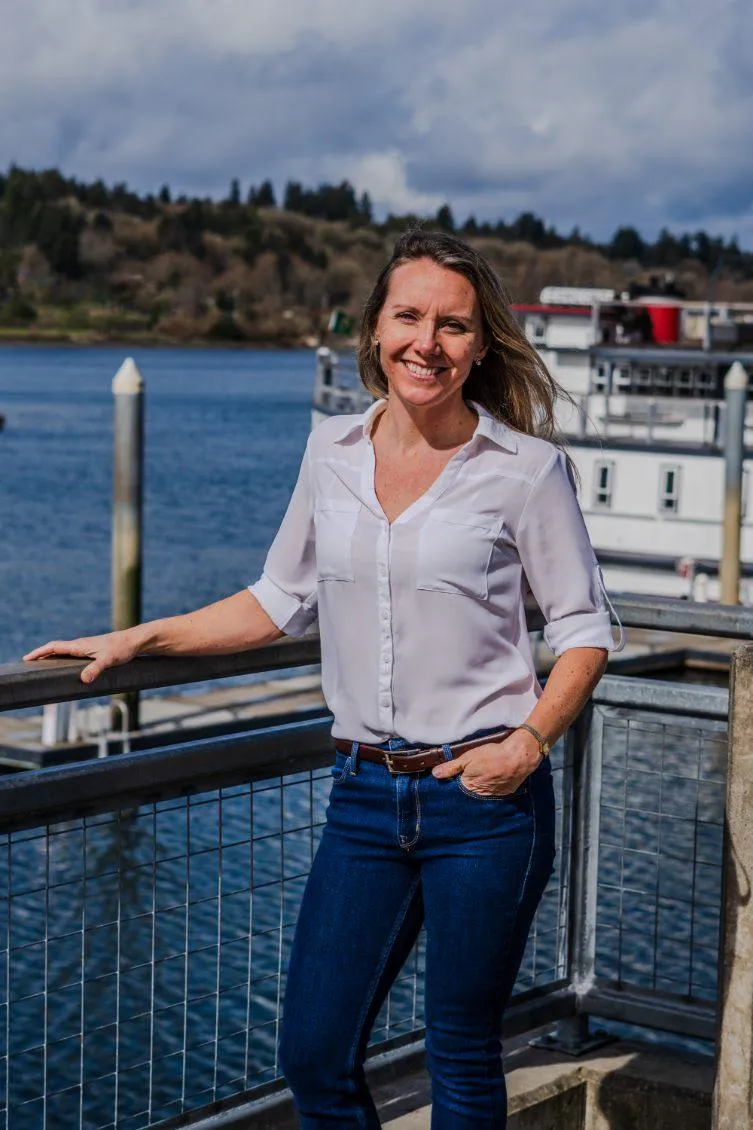Portrait of Alicia Webber, reproductive health coach, smiling warmly on a dock overlooking Bud Bay in Olympia, Washington