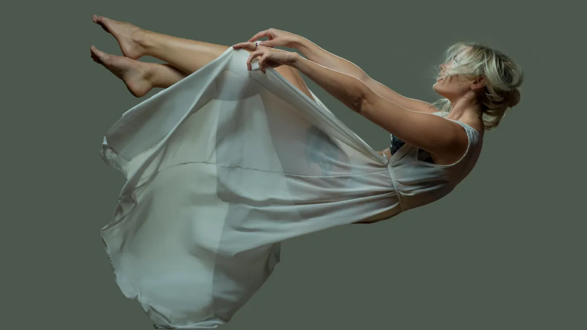 Woman floating in white fabric symbolising emotional change, midlife transition and the uncertainty of a Lifequake