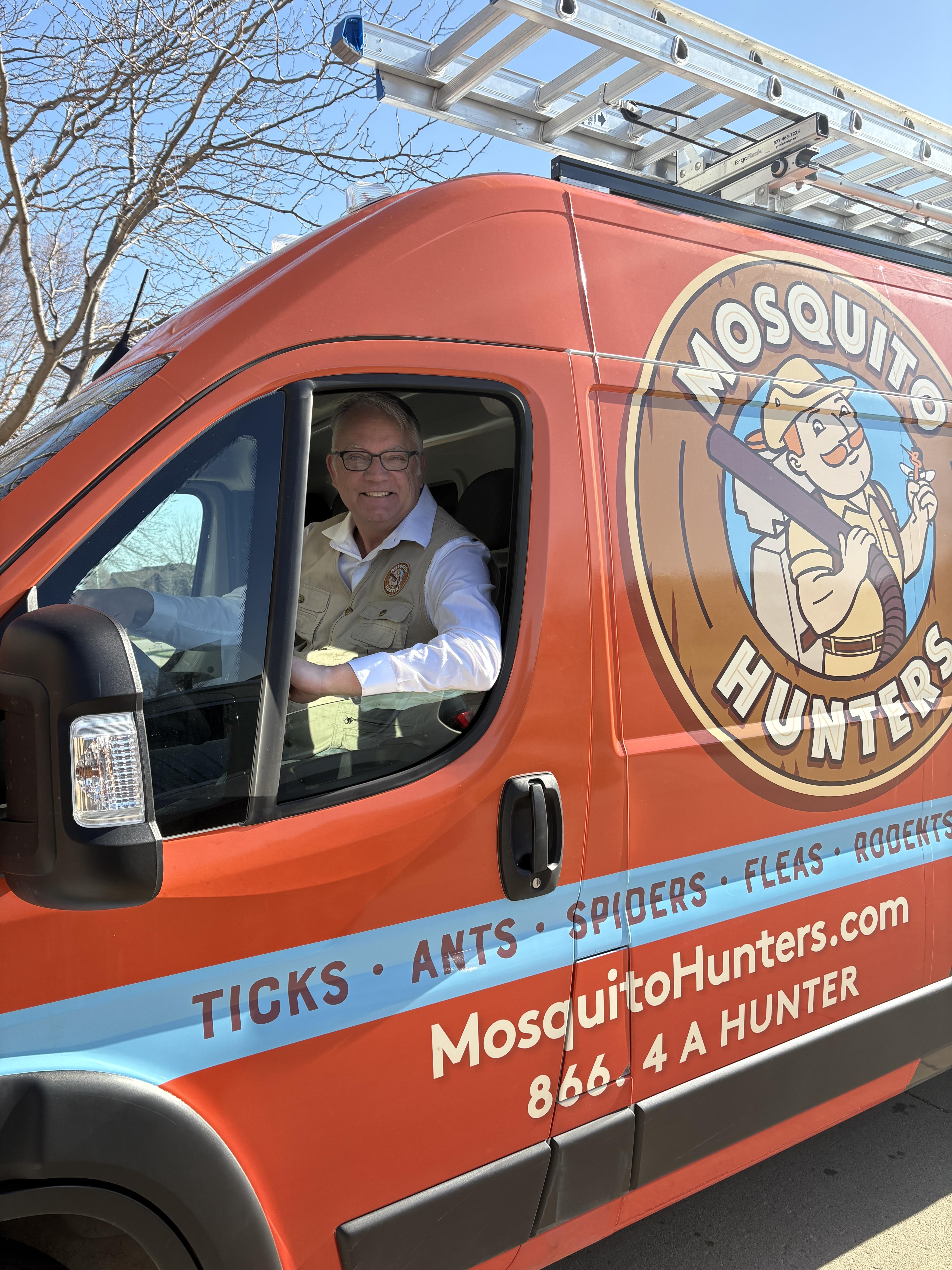 Beekeeper in yellow suit inspects honeycomb frame
