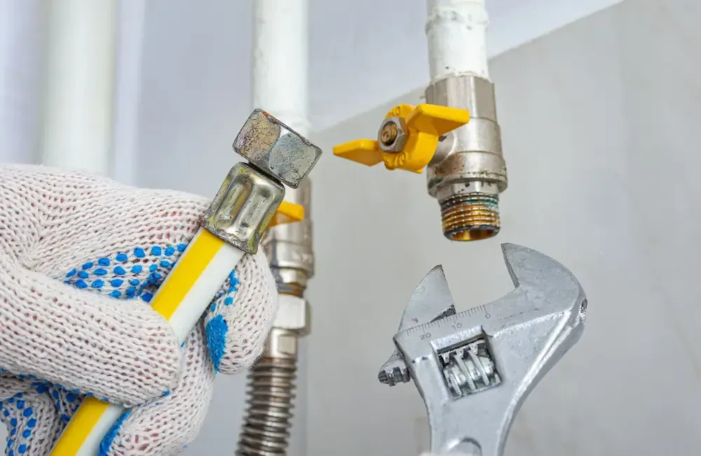 Plumber repairing a gas line connection with an adjustable wrench